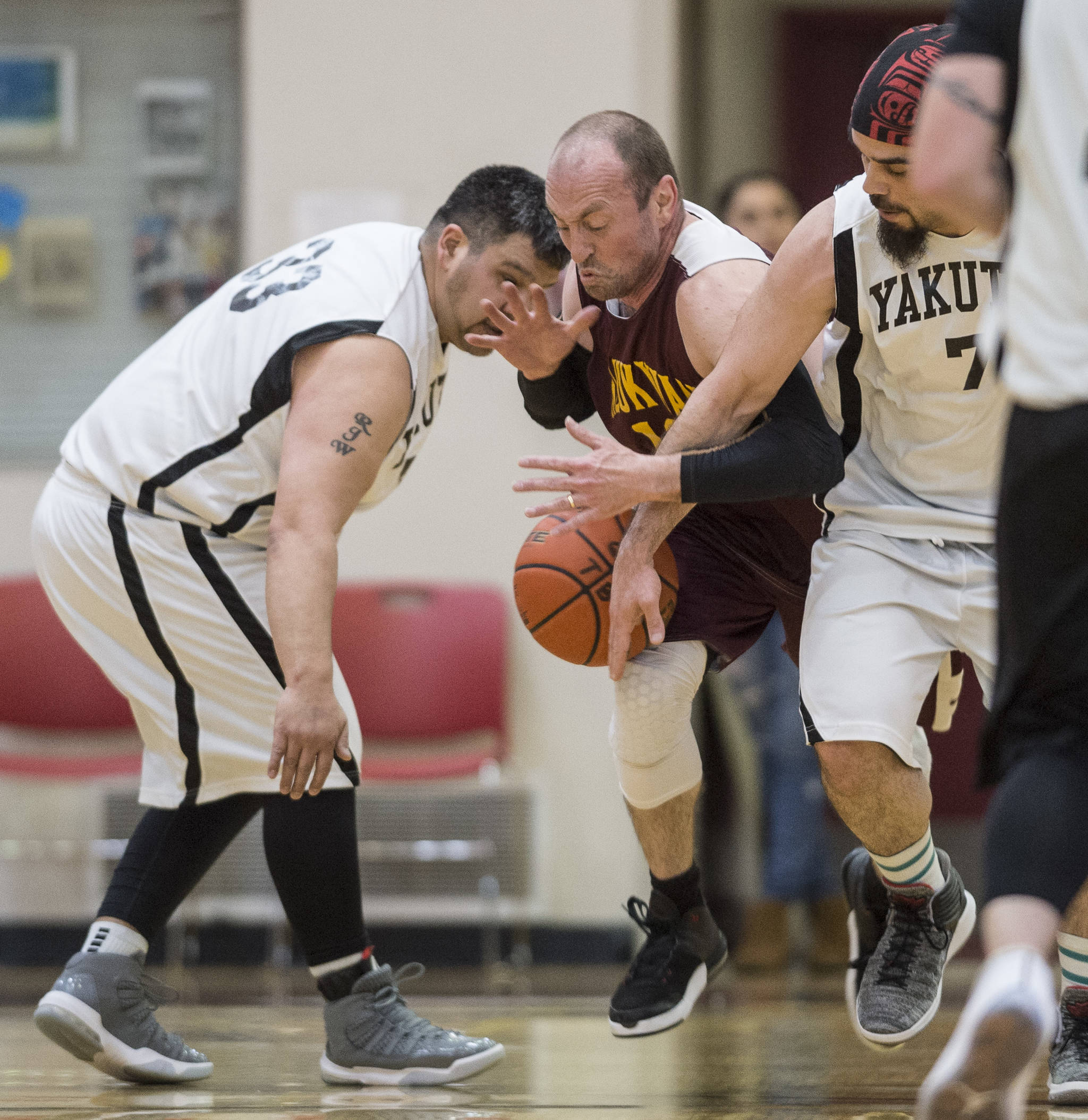 Klukwan’s Jason Shull, center, is sandwiched by Yakutat’s Ralph Wolfe, left, and JP Buller at the Juneau Lions Club 73rd Annual Gold Medal Basketball Tournament at Juneau-Douglas High School: Yadaa.at Kalé on Tuesday, March 19, 2019. Klukwan won 94-61. (Michael Penn | Juneau Empire)