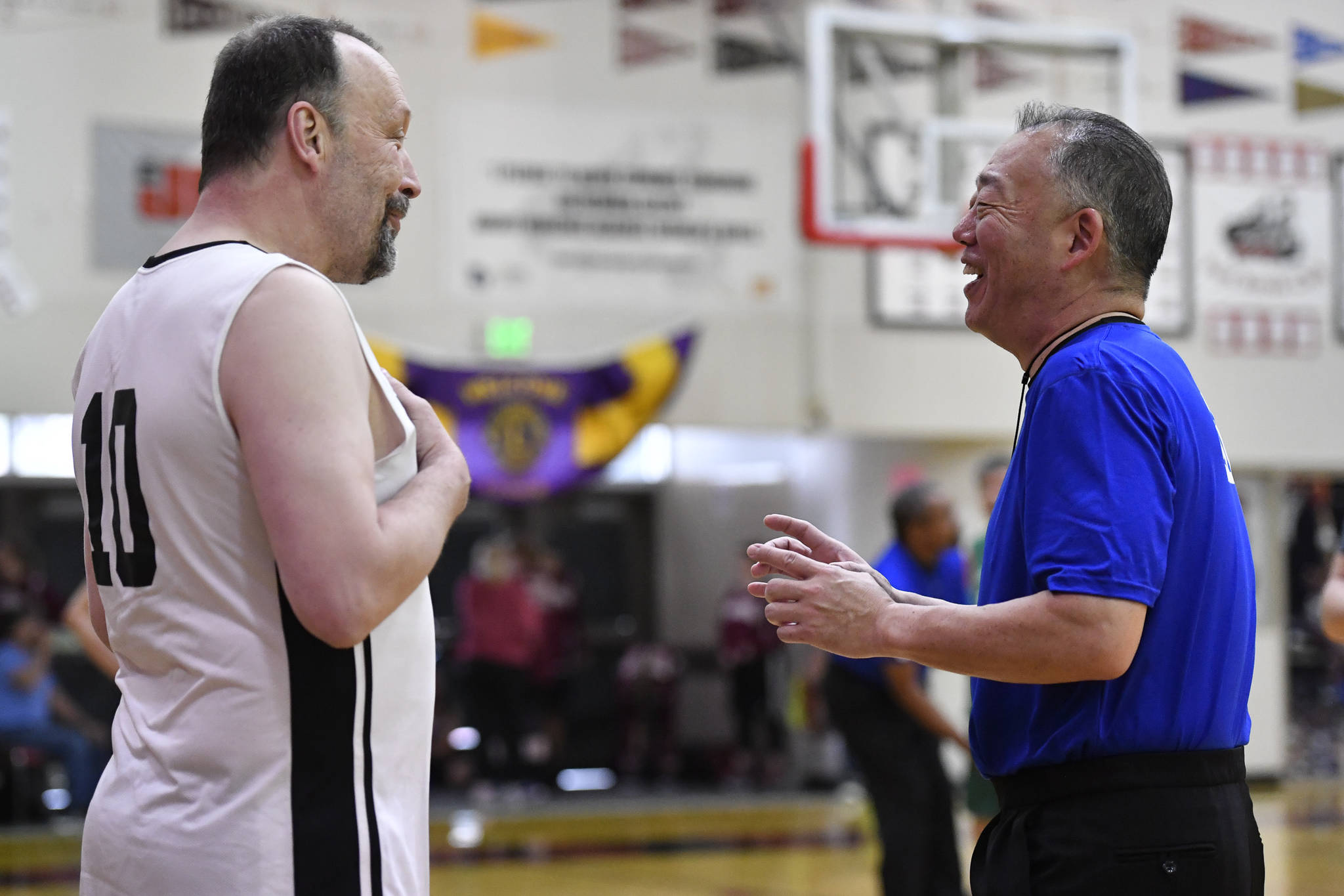 Referee Craig Tamaki, right, shares a laugh with Yakutat’s Greg Indreland during a masters bracket game against Sitka at the Juneau Lions Club 73rd Annual Gold Medal Basketball Tournament at Juneau-Douglas High School: Yadaa.at Kalé on Wednesday, March 20, 2019. Tamaki has come back to referee the tournament since 2011. (Michael Penn | Juneau Empire)