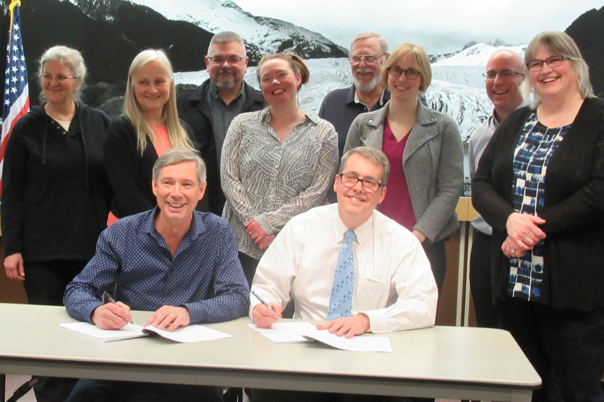 Cruise Lines International Association Alaska President John Binkley and City and Borough of Juneau City Manager Rorie Watt sign an agreement that brought litigation between CLIA and CBJ to an end Friday, March, 22, 2019. They are backed by Assembly members Michelle Bonnet Hale, Maria Gladziszewski, Rob Edwardson, Alicia Hughes-Skandijs, Loren Jones, Carole Triem, Wade Bryson and Mayor Beth Weldon.
