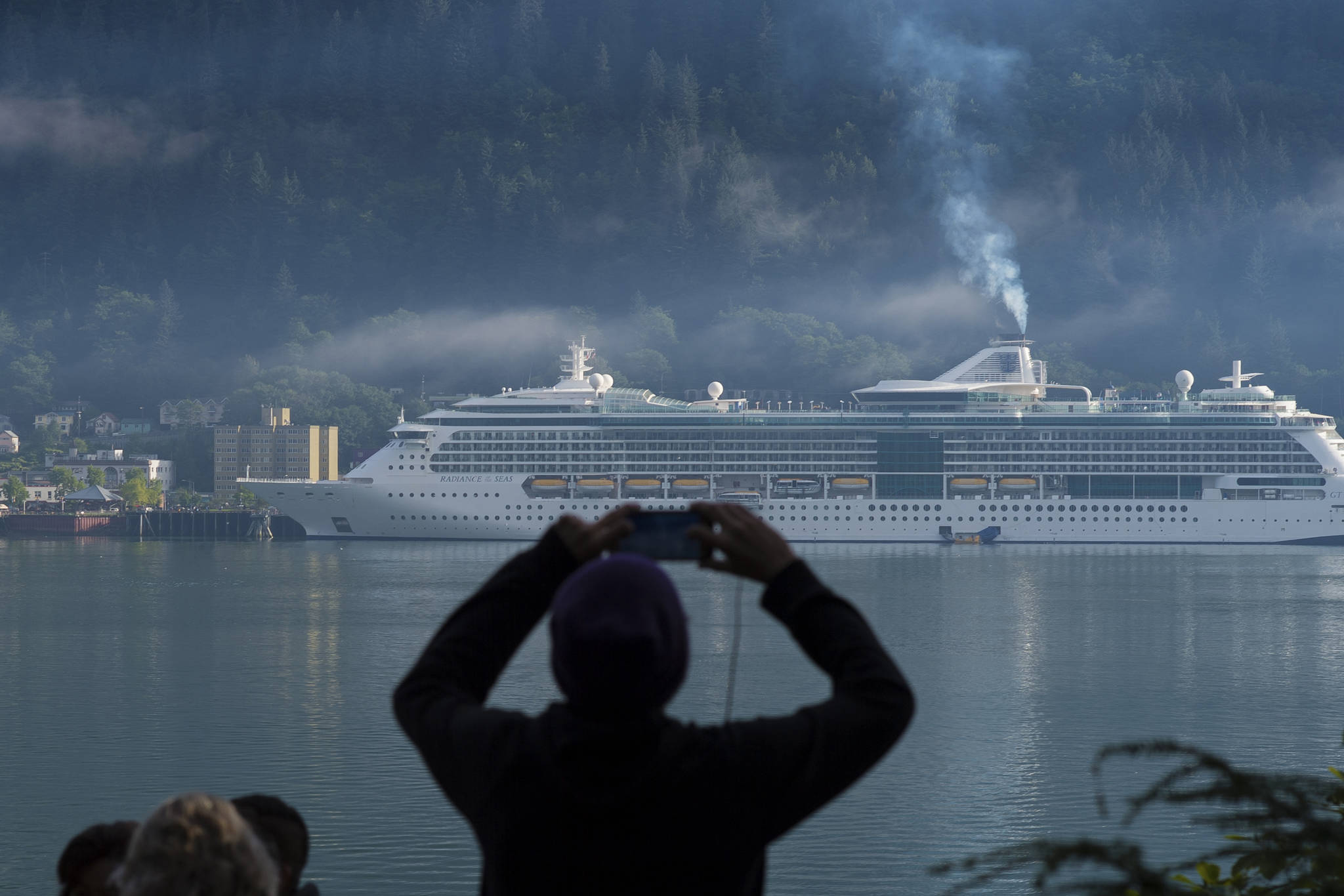 A cruise ship passenger photographs the Radiance of the Seas in Juneau’s downtown harbor on Tuesday, August 29, 2017. (Michael Penn | Juneau Empire File)
