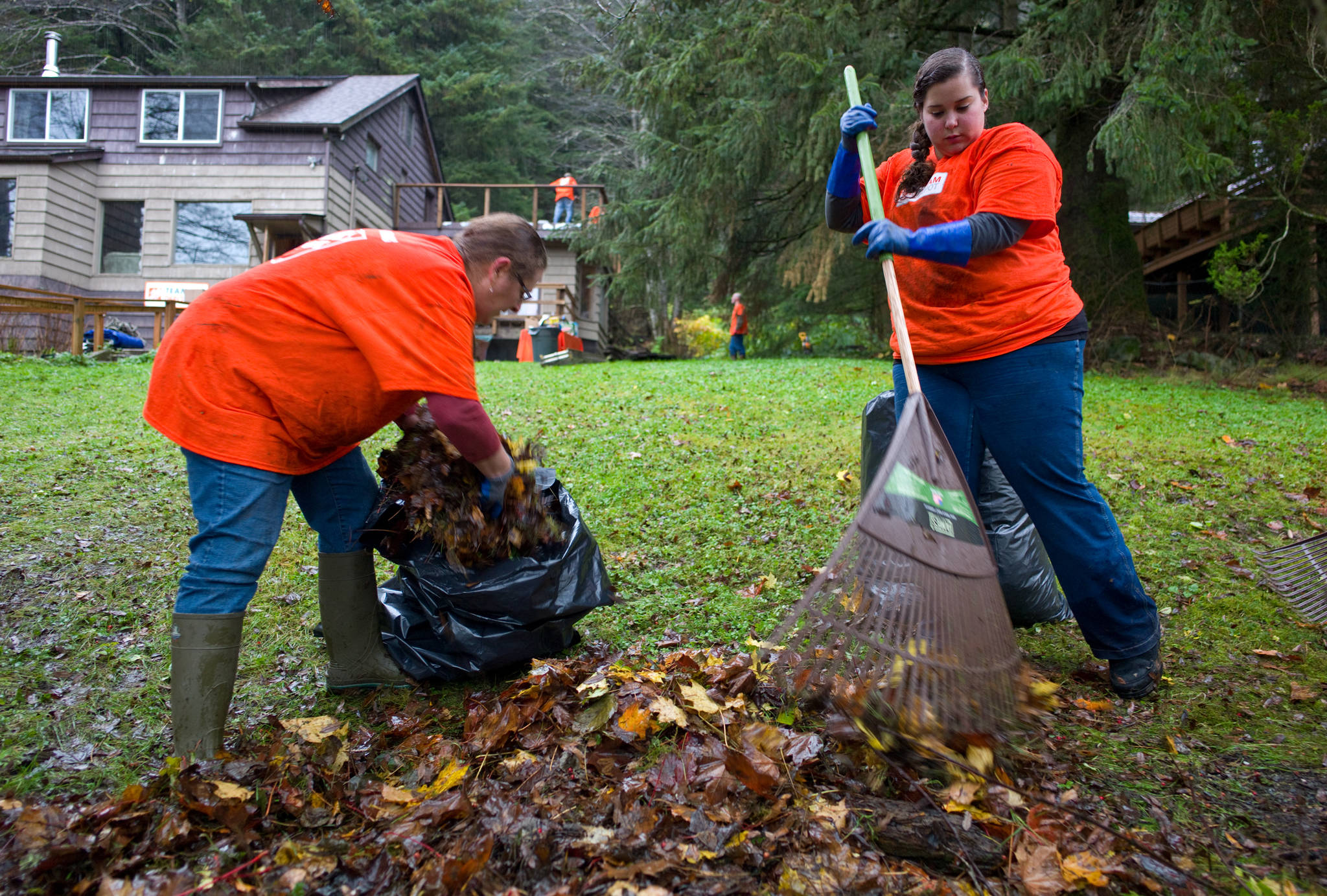 In this October 2014 photo, Cindy Roccodero, left, and Sara Velasquez clean up the yard of Michael Leach. Team Depot, The Home Depot associate-led volunteer force, together with Helping Hands of Juneau, worked to transform the home of a 84-year-old Korean War veteran. (Michael Penn | Juneau Empire File)