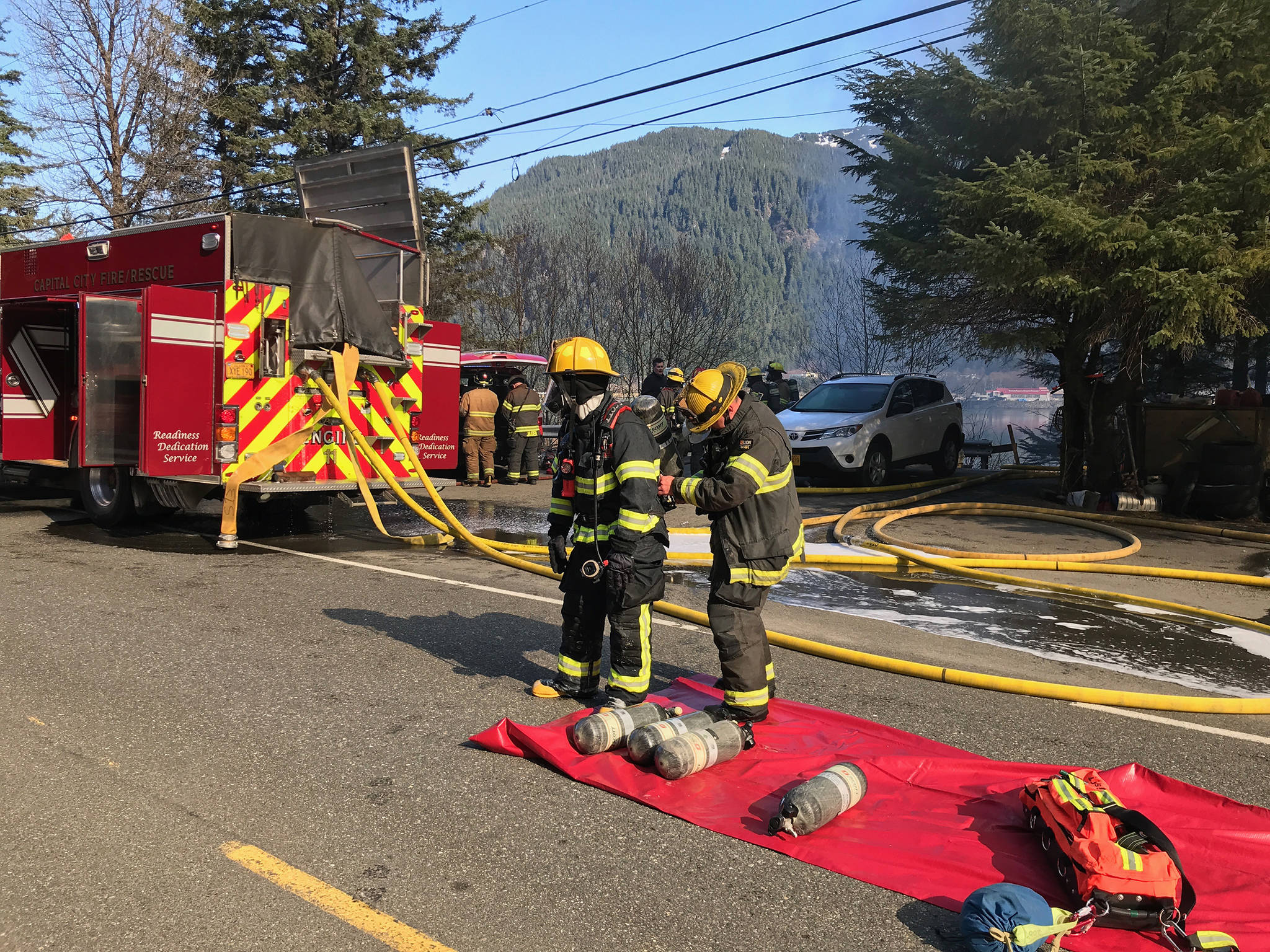 Firefighters are seen at the scene of a house fire on North Douglas Highway on Thursday, March 28, 2019. (Michael Penn | Juneau Empire)