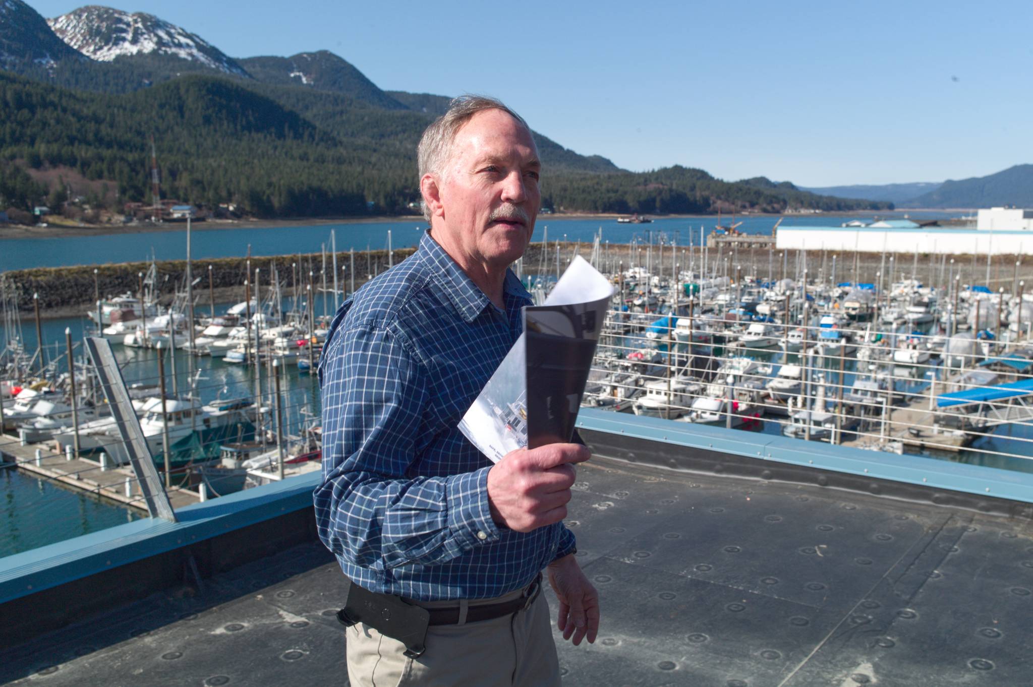 From the roof of their new building over looking Harris Harbor in Juneau, Retired U.S. Coast Guard Captain Ed Page, Executive Director of the Alaska Marine Exchange, explains Wednesday, March 27, 2019, how the exchange came about and how it now keeps track of ships in Alaska waters and beyond. (Michael Penn | Juneau Empire)