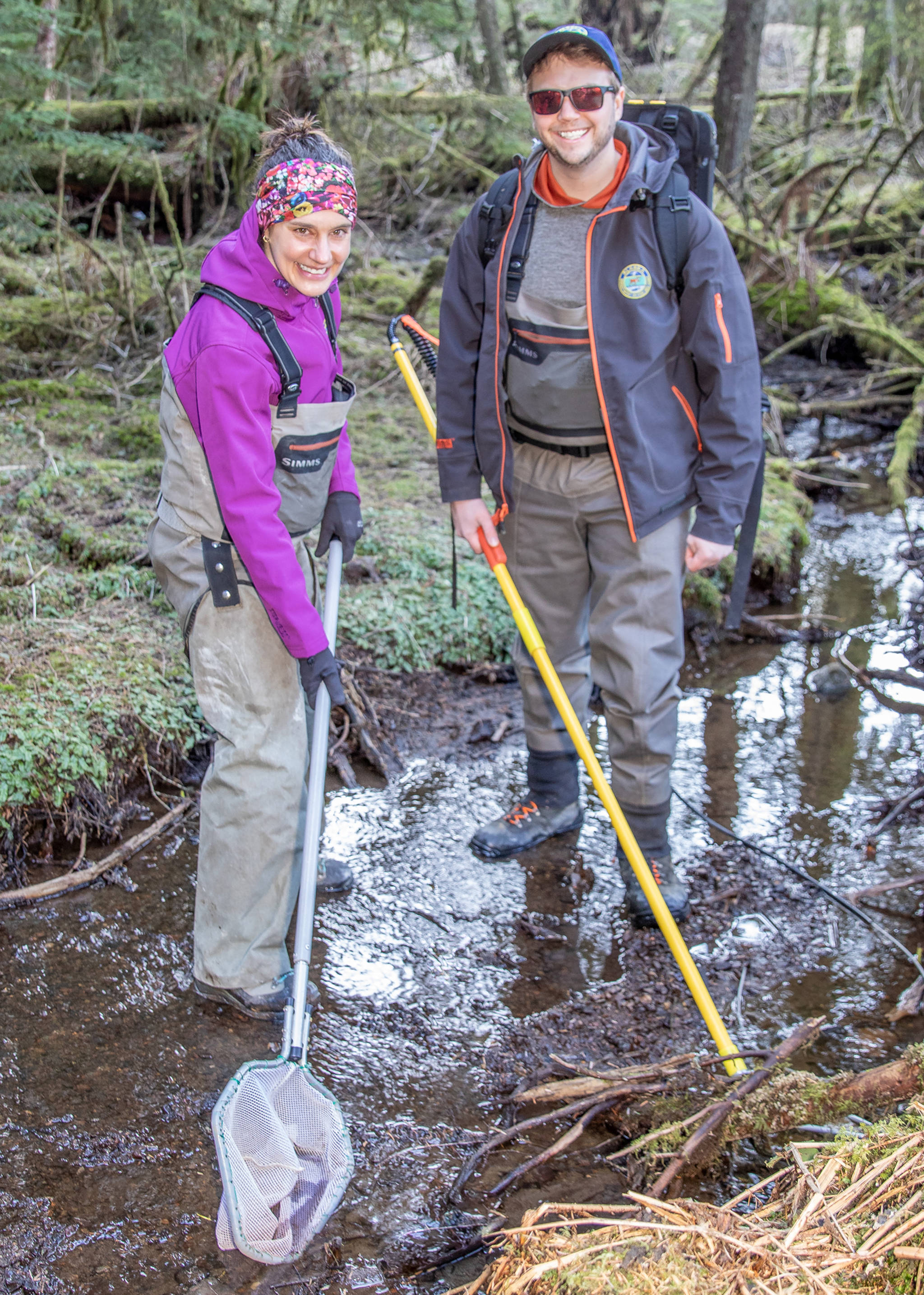 April 21, 2019: Even on a field work day, Nicole Legere and Dylan Krull, Habitat Biologists with the Alaska Department of Fish and Game manage to look sharp and well-dressed for the task. This day they were electrofishing a small tributary to Auke Lake looking for coho salmon. Both are wearing waders and boots by Simms and ADF&G logo jackets from Drift Creek Outdoors. Their most important accessory: a Smith Root LR-24 backpack electrofisher. They found coho!