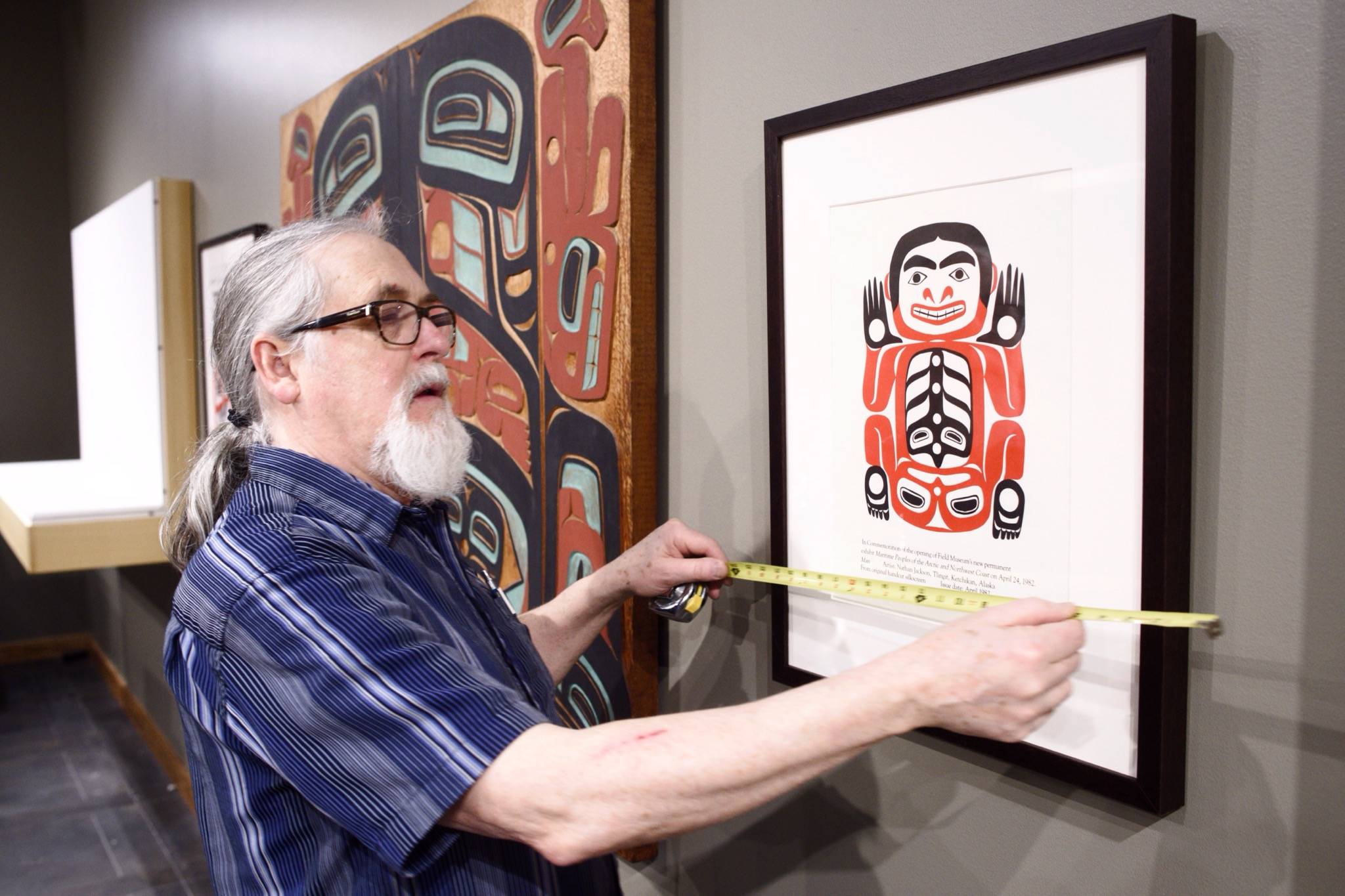 Paul Gardinier, an exhibit specialist, works to install a Nathan Jackson retrospective in the gallery at the Walter Soboleff Center on Monday, March 25, 2019. (Michael Penn | Juneau Empire)