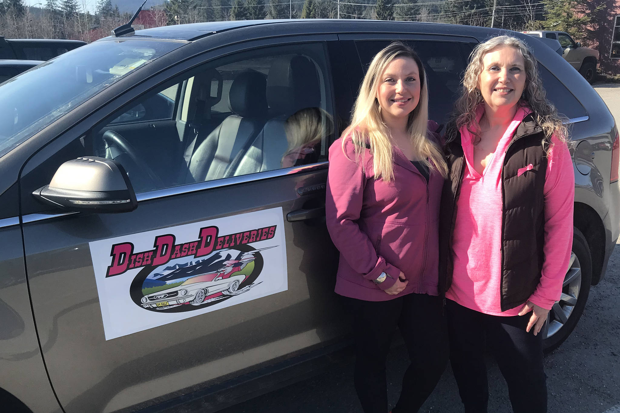 Corinna Nelson-Felkl, left, and Colleen Belardi, right, owners of Dish Dash Deliveries stand next to their logo on Friday, March 29, 2019. Dish Dash Deliveries will start operating on May 1. (Mollie Barnes | Juneau Empire)