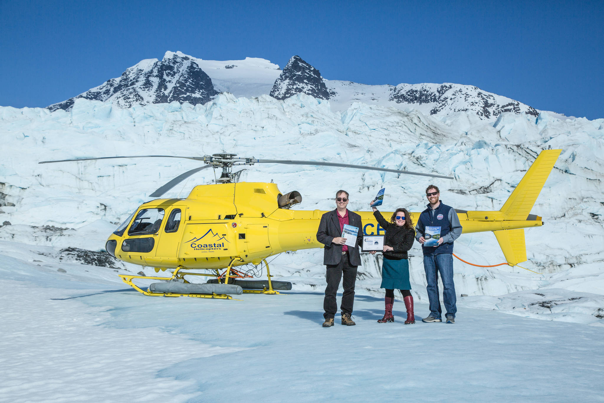 Robert Venables, Southeast Conference executive director, Meilani Schijvens, Rain Coast Data director and Alec Mesdag, incoming president of the Southeast Conference Board of Directors show off the Southeast Alaska 2020 Economic Plan, the NADO award and Southeast Alaska by the Numbers publication on the Juneau icefield. (Courtesy Photo | Heather Holt)