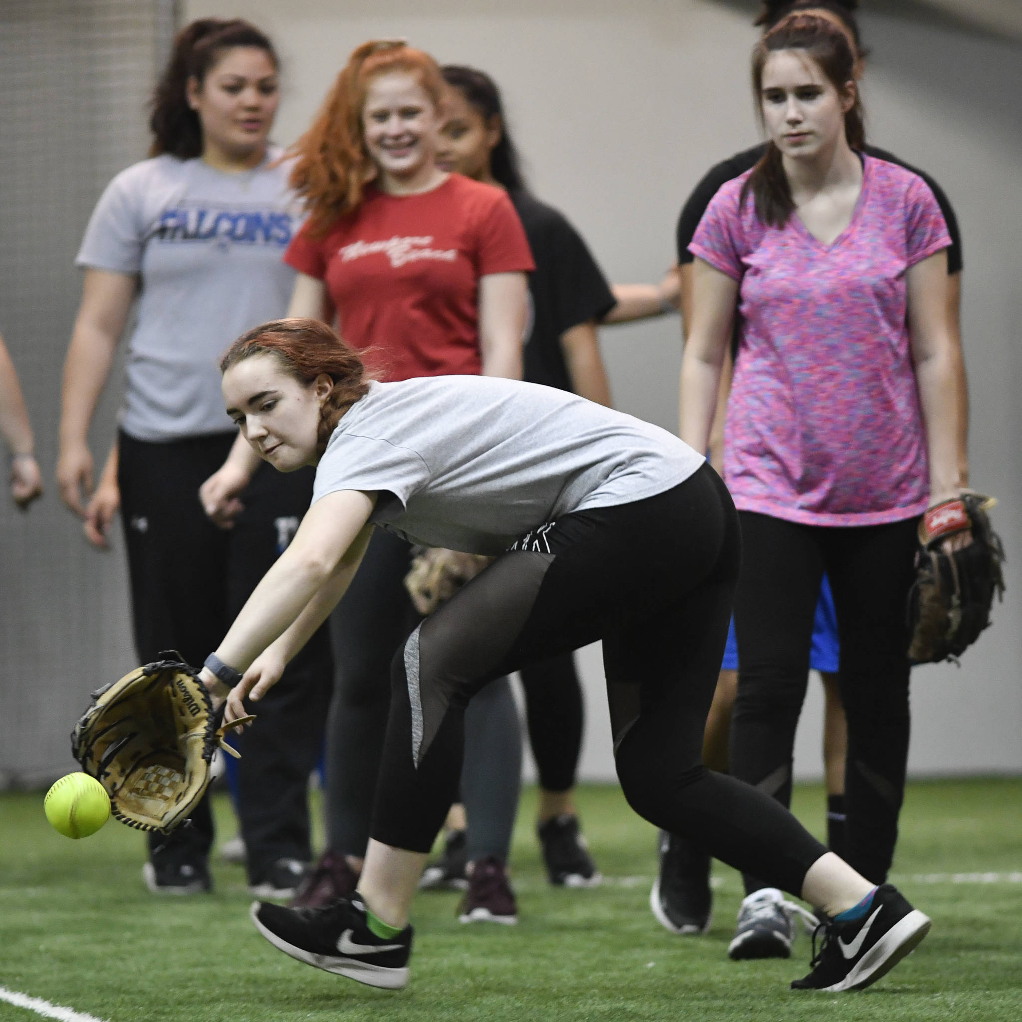 Senior Emily Bowman reaches for the ball during Thunder Mountain High School softball practice at the Wells Fargo Dimond Park Field House on Tuesday, April 2, 2019. (Michael Penn | Juneau Empire)
