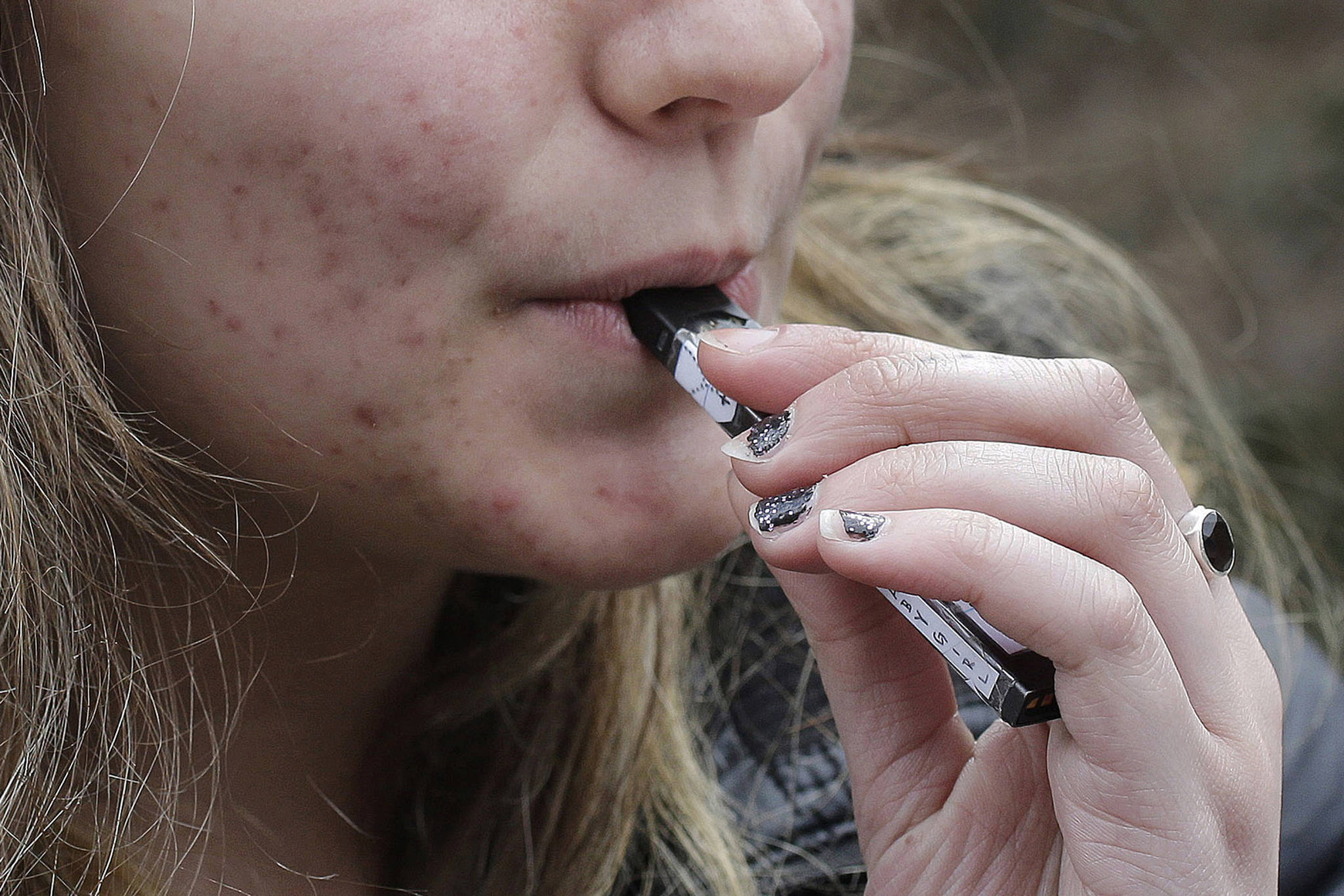In this April 11, 2018 photo, a high school student uses a vaping device near a school campus in Cambridge, Massachusetts. (Steven Senne | Associated Press File)