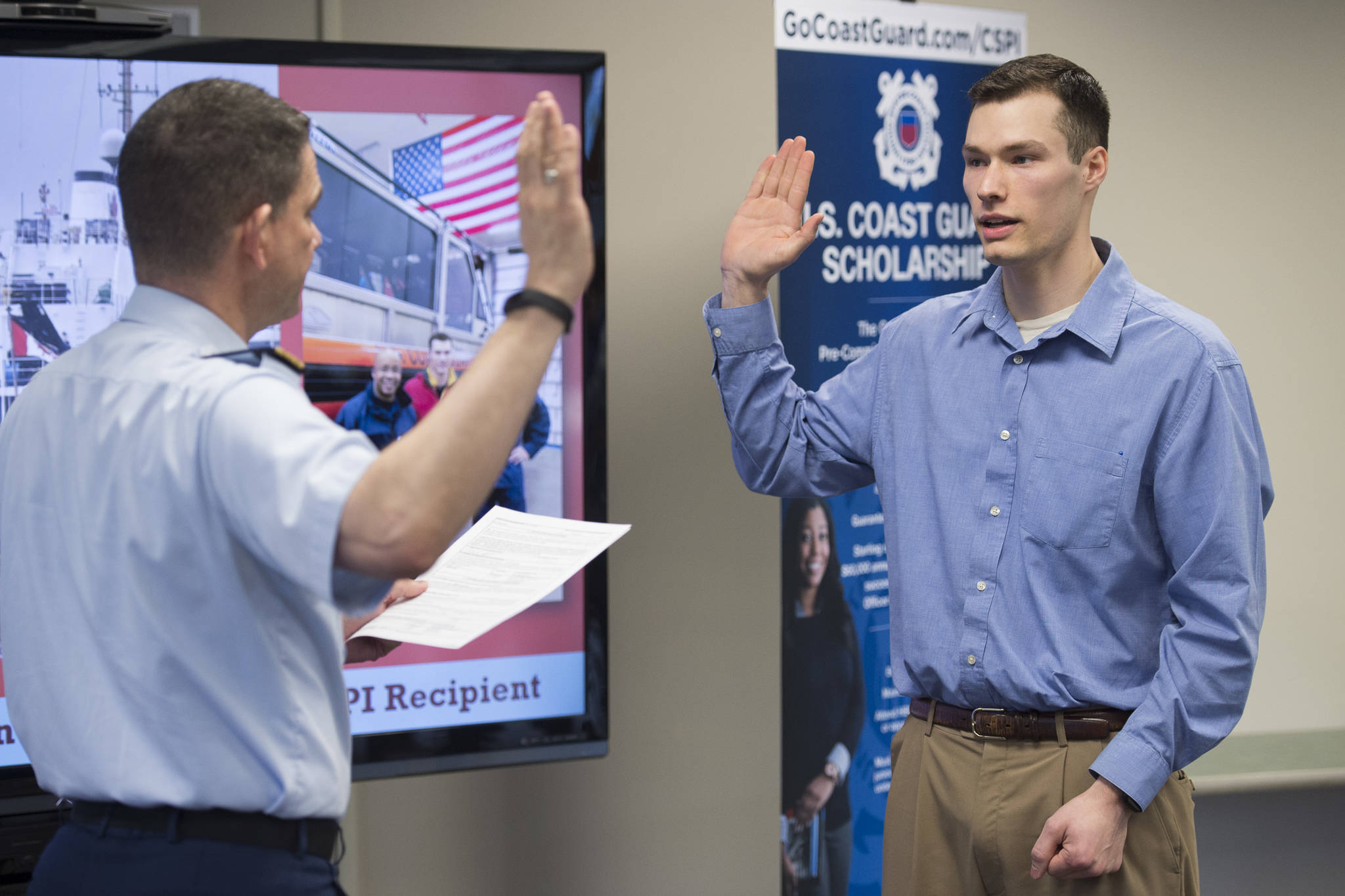Logan Holt, 21, a business major at the University of Alaska Southeast, is sworn into the U.S. Coast Guard by Rear Admiral Matthew Bell Jr., commander of the 17th Coast Guard District, at UAS on Tuesday, April 9, 2019. Holt is the first recruit from UAS to be accepted into the Coast Guard’s College Student Pre-Commissioning Initiative program. (Michael Penn | Juneau Empire)
