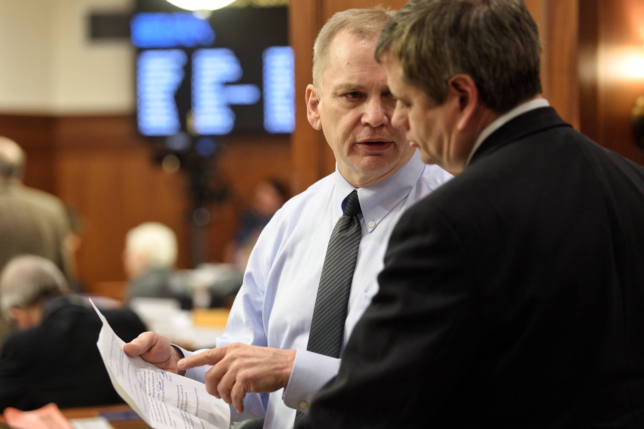 Rep. Mark Neuman, R-Big Lake, left, speaks with Rep. Chris Tuck, D-Anchorage, on the House floor as amendments to the budget are proposed on Tuesday, April 9, 2019. (Michael Penn | Juneau Empire)