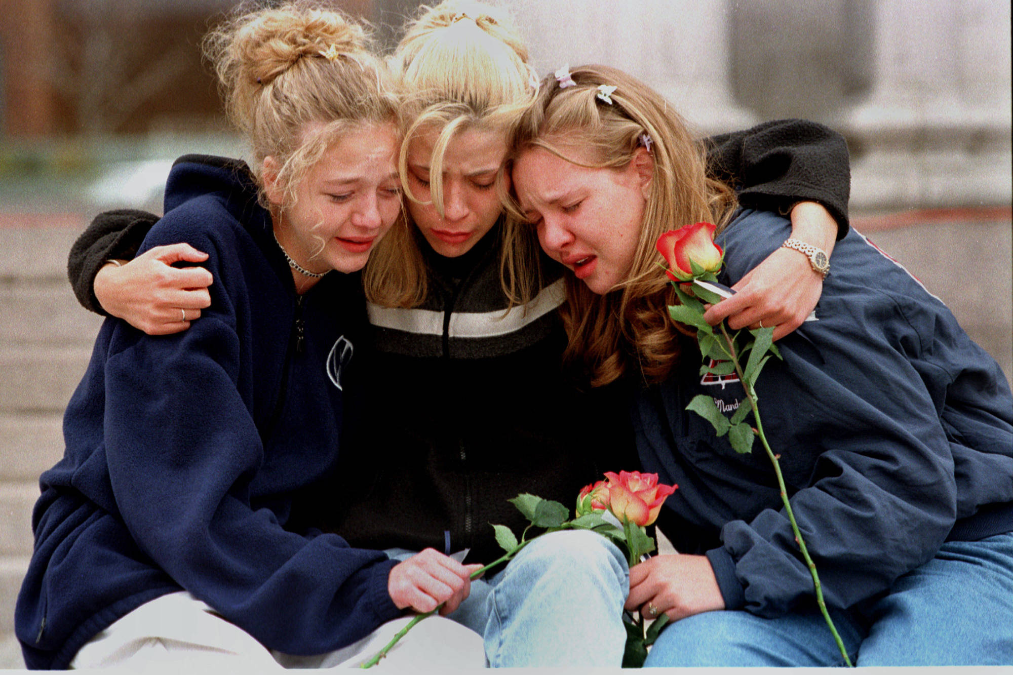 In this April 21, 1999 photo, from left, Rachel Ruth, Rhianna Cheek and Mandi Annibel, all 16-year-old sophomores at Heritage High School in Littleton, Colorado, console each other during a vigil service to honor the victims of the shooting spree in Columbine High School. Twelve students and one teacher were killed in a murderous rampage at the school on April 20, 1999 by two students who killed themselves in the aftermath. (Laura Rauch | The Associated Press File)