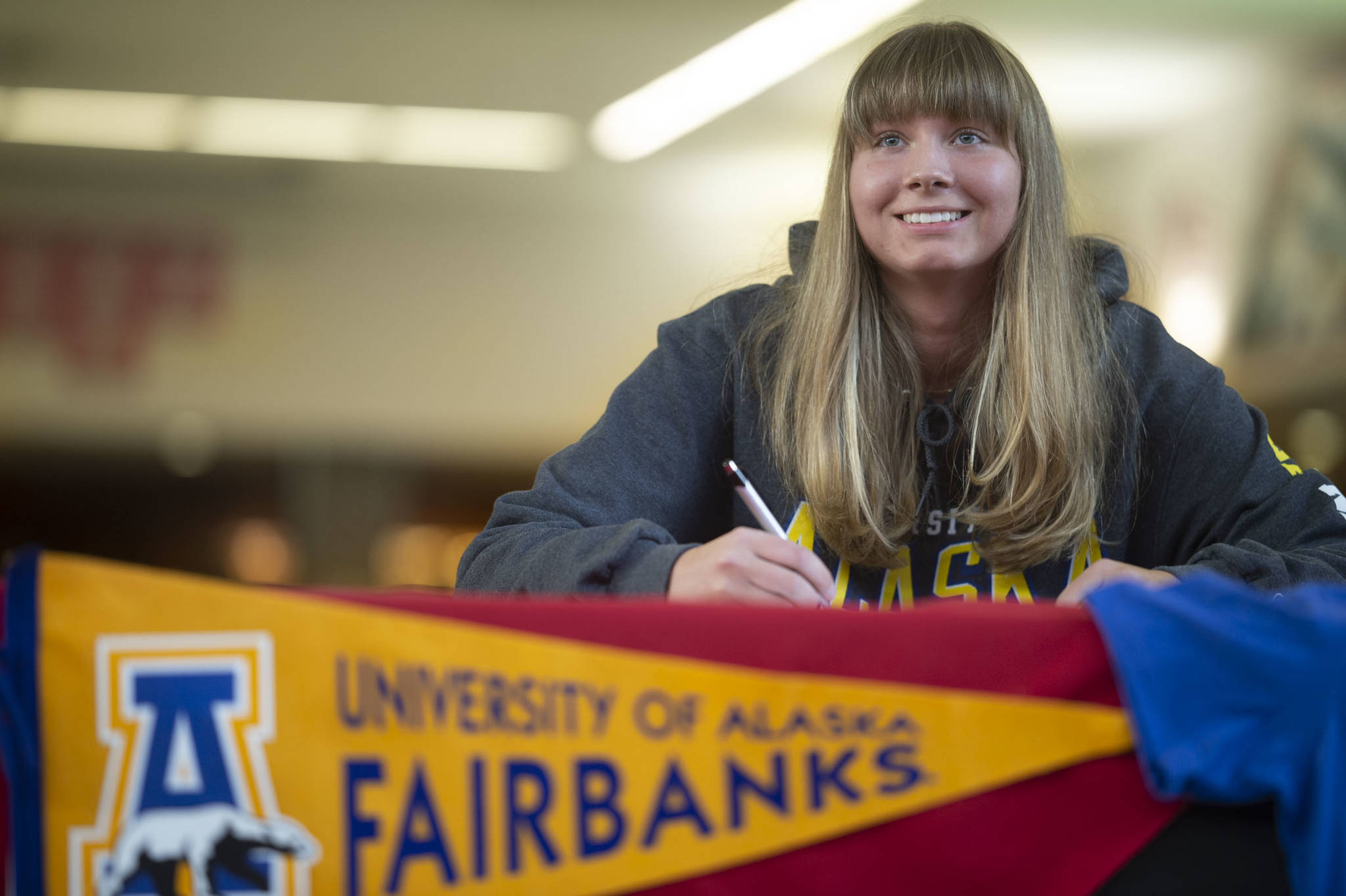 Caitlin Pusich, a senior at Juneau-Douglas High School, signs a letter of intent to go to school and play basketball for the University of Alaska Fairbanks at JDHS on Tuesday, April 16, 2019. (Michael Penn | Juneau Empire)