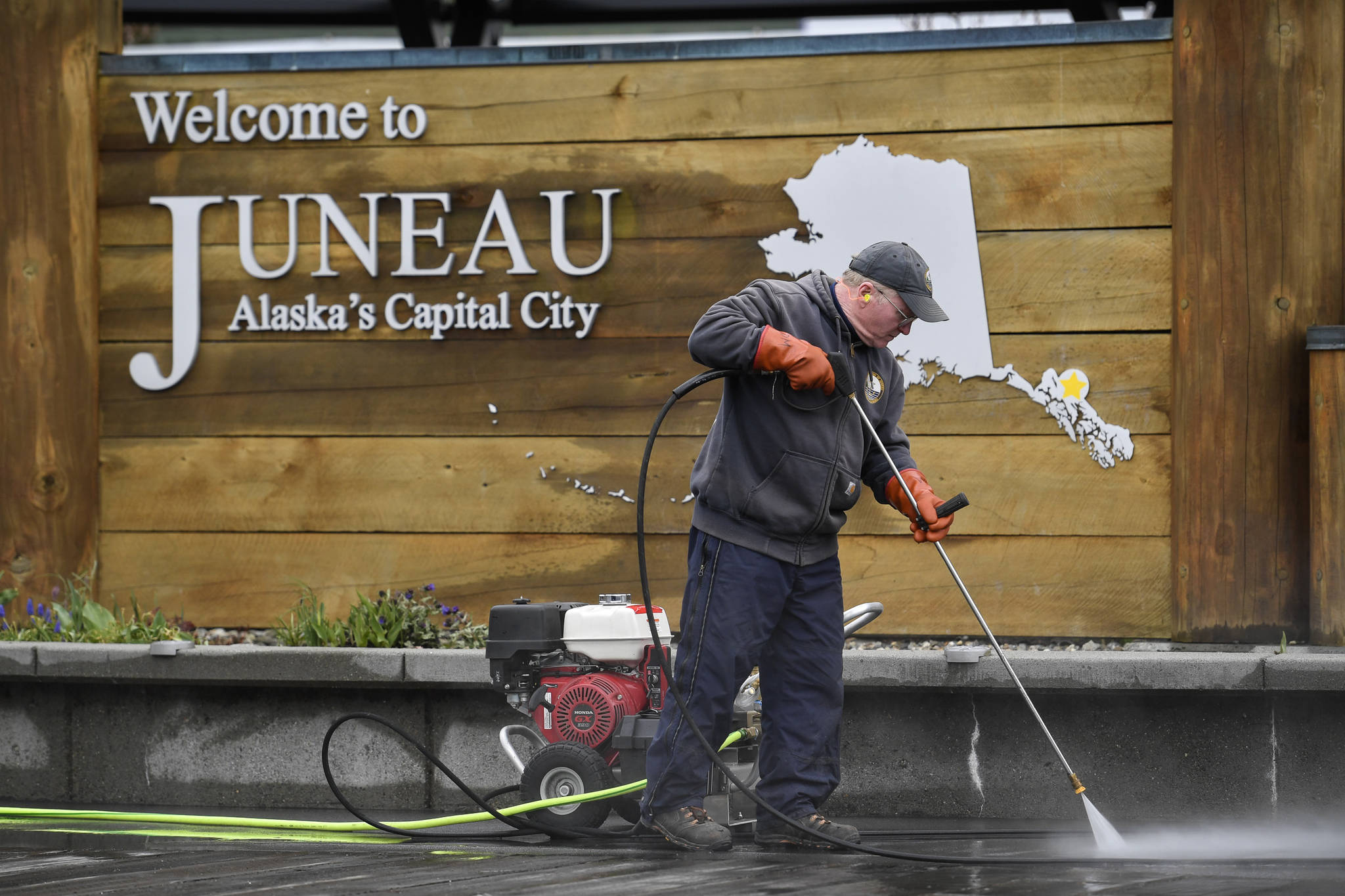 Dave Morgan, of the citys Dock and Harbors department, pressure washes the sidewalk near the downtown Visitors Center on Friday, April 19, 2019. (Michael Penn | Juneau Empire)
