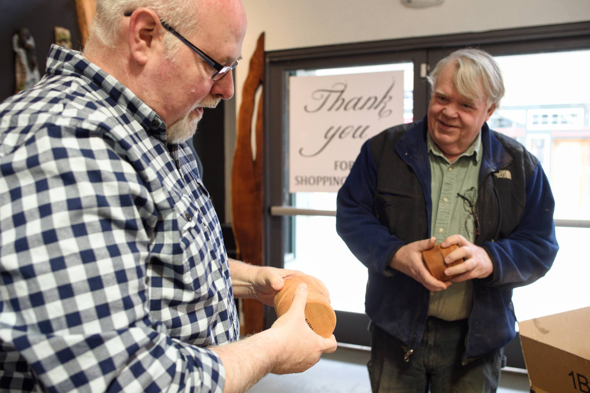 Dean Graber, owner of Rainforest Custom, left, talks with Ed Hansen on Thursday, April 25, 2019, about Hansen’s wooden toys and boxes that will be for sale at Graber’s new shop on South Franklin Street. (Michael Penn | Juneau Empire)