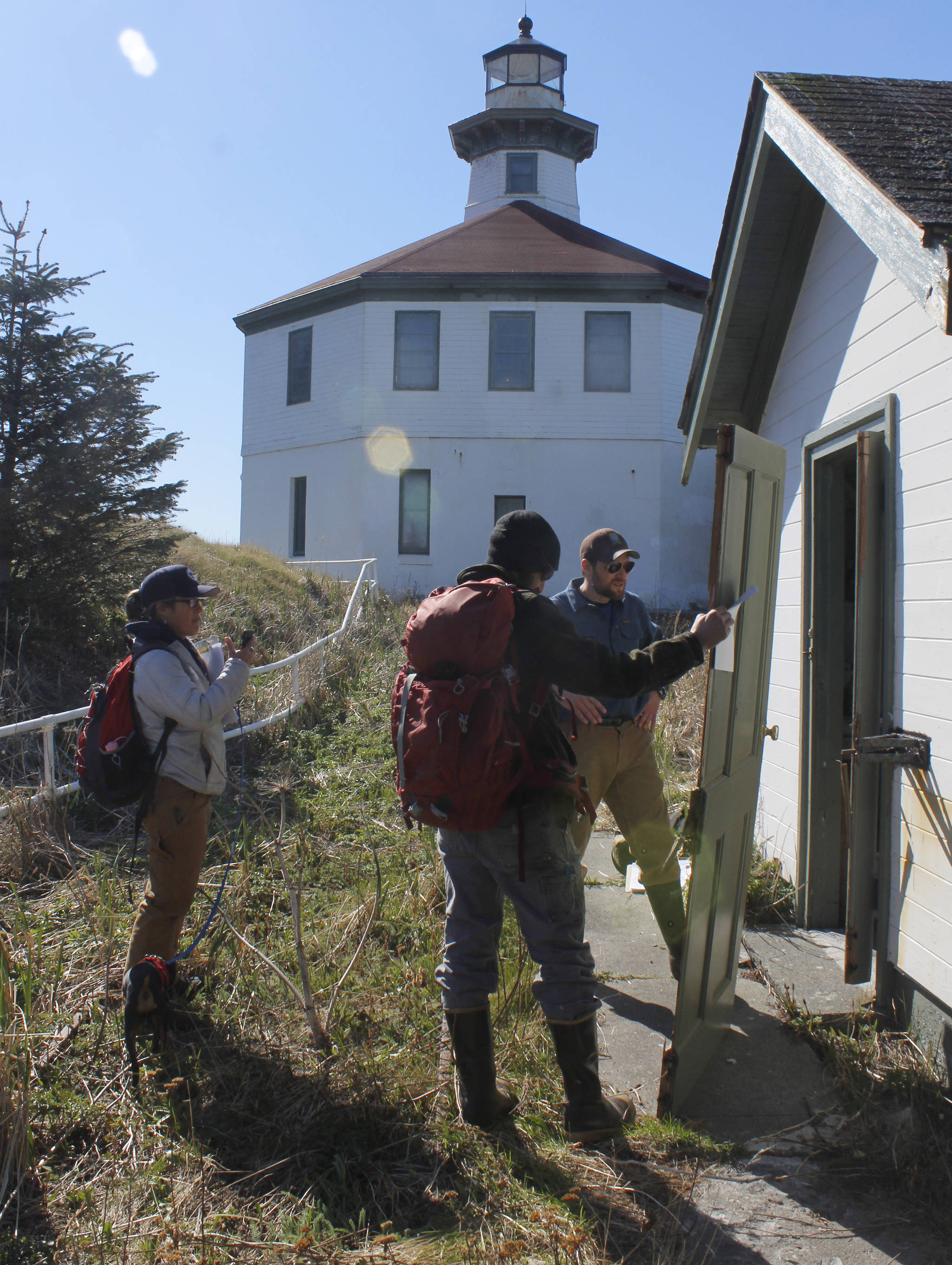 Eldred Rock Lighthouse Preservation Association Executive Director Sue York and board members Justin Fantasia and Jonathan Wood examine a broken door at Eldred Rock Lighthouse on Monday, April 29, 2019. (Alex McCarthy | Juneau Empire)