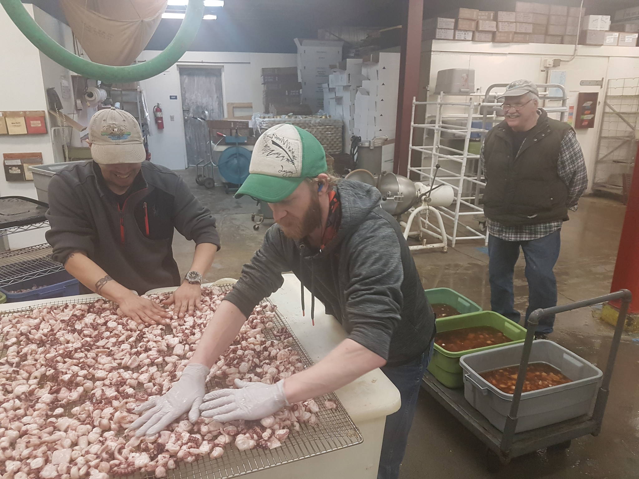 Alaska Seafood Company owner Dick Hand, right, watches as employees prepare Rick Pruett’s octopus to be smoked. (Courtesy photo | Rick Pruett)