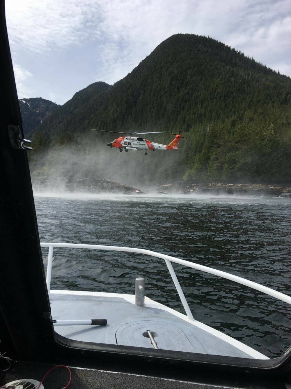 A Coast Guard Air Station Sitka MH-60 Jayhawk helicopter crew hovers while searching for a survivor from a report of two aircraft colliding in the vicinity of George Inlet near Ketchikan, Alaska, May 13, 2019. Ten survivors of the crash had reportedly swam to shore and were rescued by Coast Guard aircrews while the search continues for two people still reported to be missing from the crash. (Courtesy photo | Ryan Sinkey)