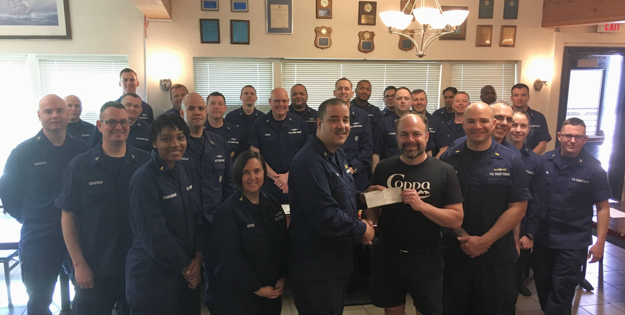 Coppa co-owner Marc Wheeler presents a check for $500 to OSC Robert Luna, head of the U.S. Coast Guard Chief Petty Officers Association in Juneau. Also present is the entire chief’s mess. (Courtesy Photo)
