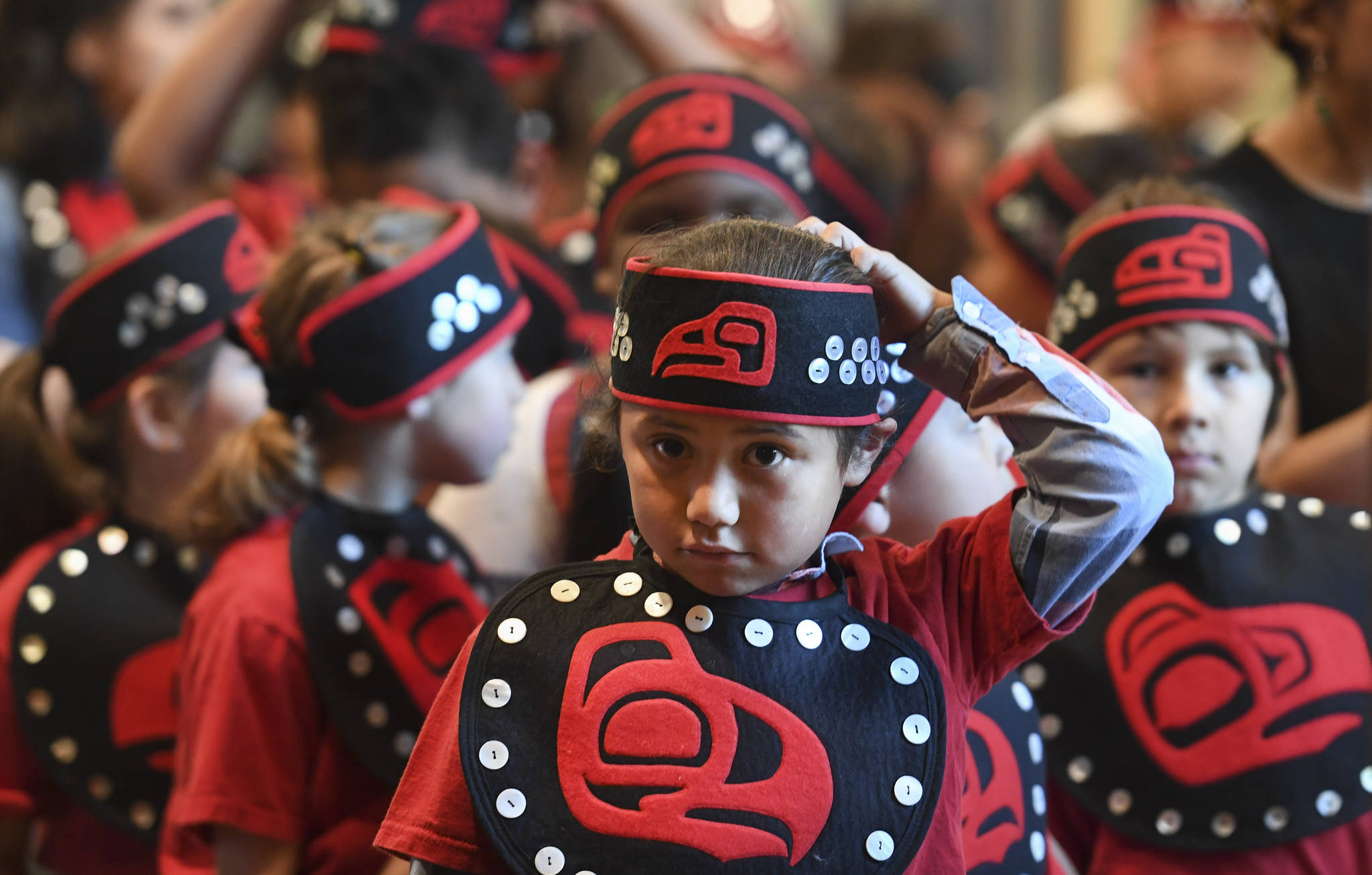 First-grader Shaunde Ahshadanek adjusts his headband as he lines up with his classmates at the Tlingit Culture Language & Literacy 5th Grade Promotion held in the clan house at the Walter Soboleff Center on Wednesday, May 22, 2019. (Michael Penn | Juneau Empire)