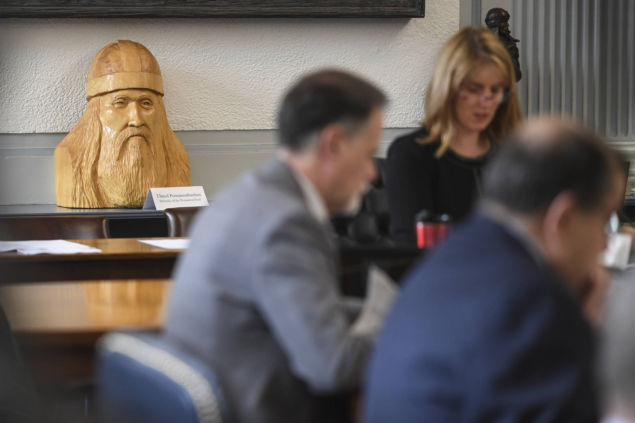 A carved statue titled “Uhtred Permanentfundsen, Defender of the Permanent Fund,” sits on the counter as Sen. Natasha von Imhof, R-Anchorage, chairs the Senate Finance Committee at the Capitol on Monday, May 6, 2019. Co-Chair Bert Stedman, R-Sitka, bought the carving from Petersburg artist Robert Fudge recently and stationed it at the front of the Senate Finance Committee room. (Michael Penn | Juneau Empire File)