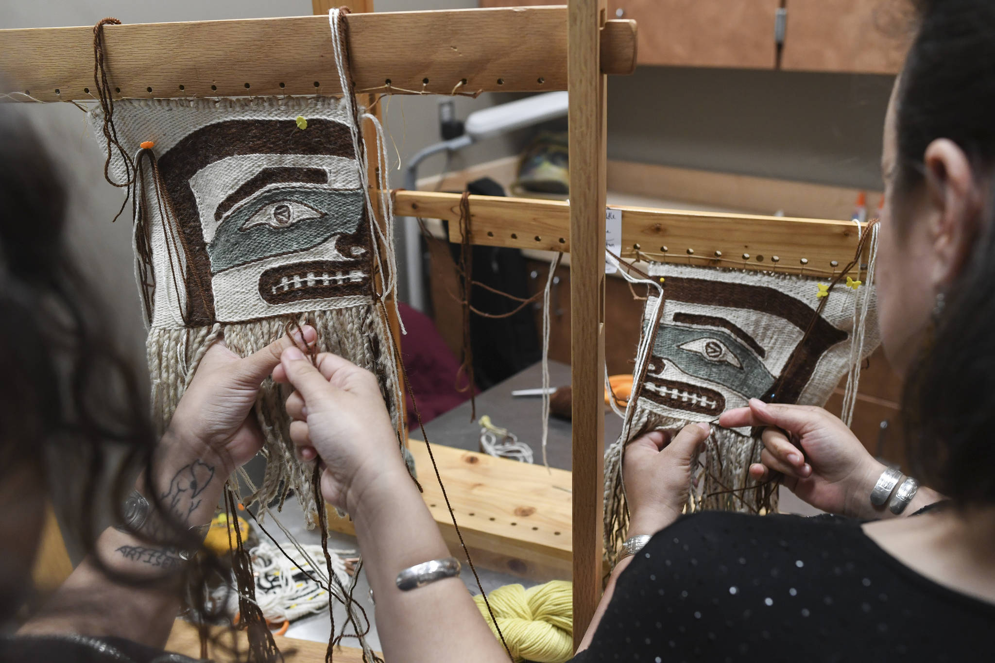 Anastasia Hobson-George, left, works with weaver Lily Hope on Chilkat legging weavings as the Artist-in-Residence at the Walter Soboleff Center on Wednesday, May 22, 2019. (Michael Penn | Juneau Empire)