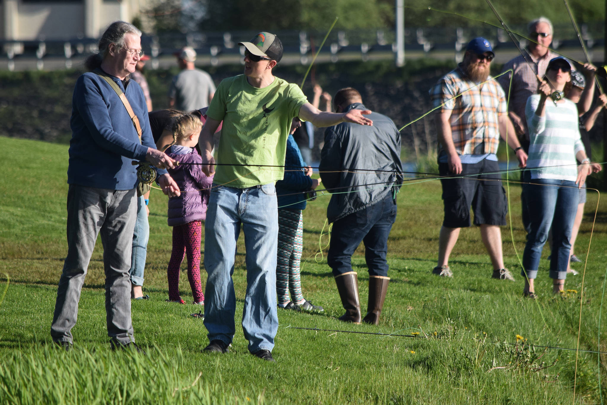 Fly fishing volunteer instructor Drew Stafford, right, helps out a man learning to fly cast during Fly Casting Night at Twin Lakes on Wednesday, May 22, 2019. (Nolin Ainsworth | Juneau Empire)