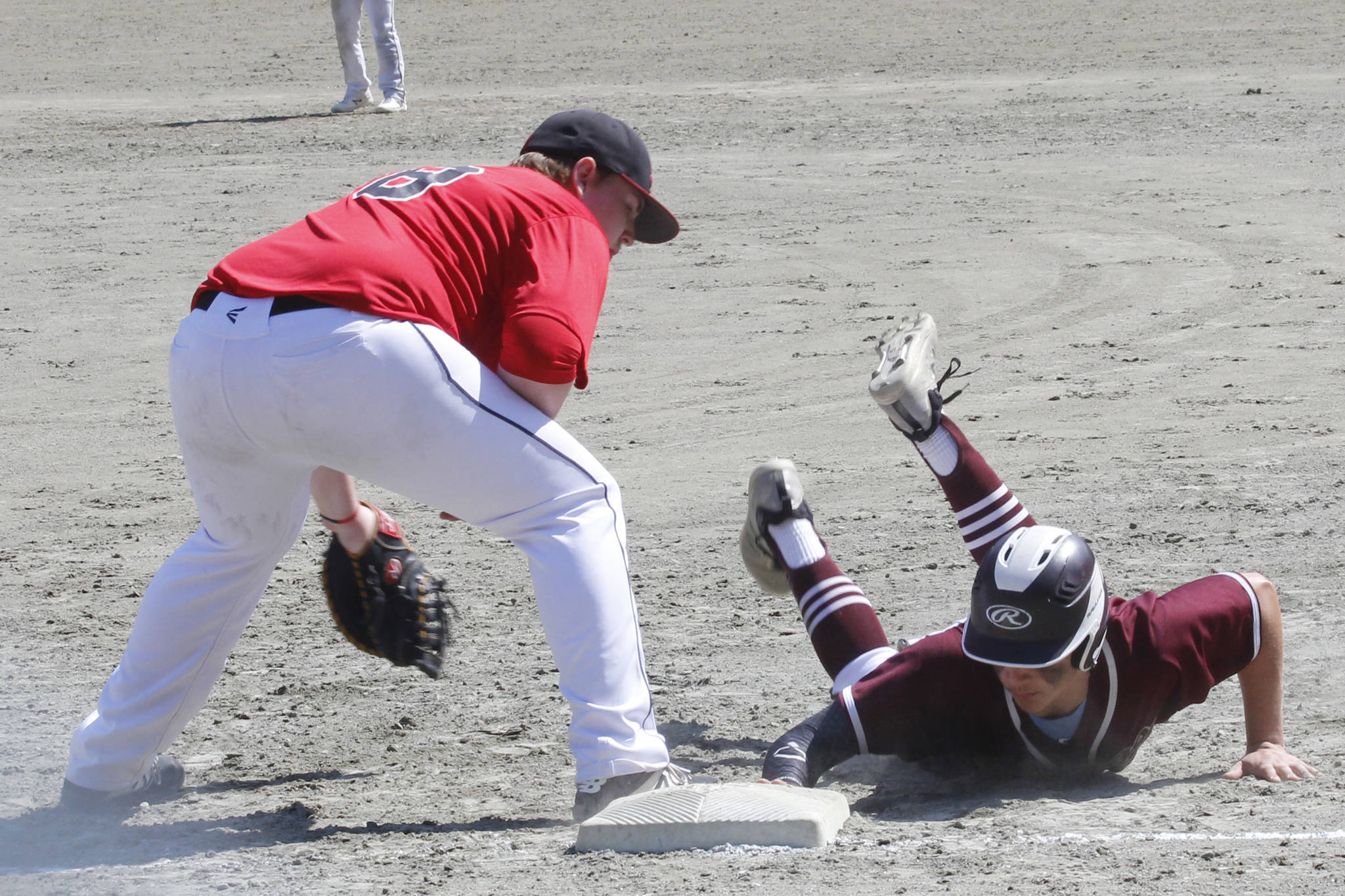 A Ketchikan runner dives back to first base on a pick-off attempt in the Region V title game on Saturday, May 25, 2019. (Alex McCarthy | Juneau Empire)