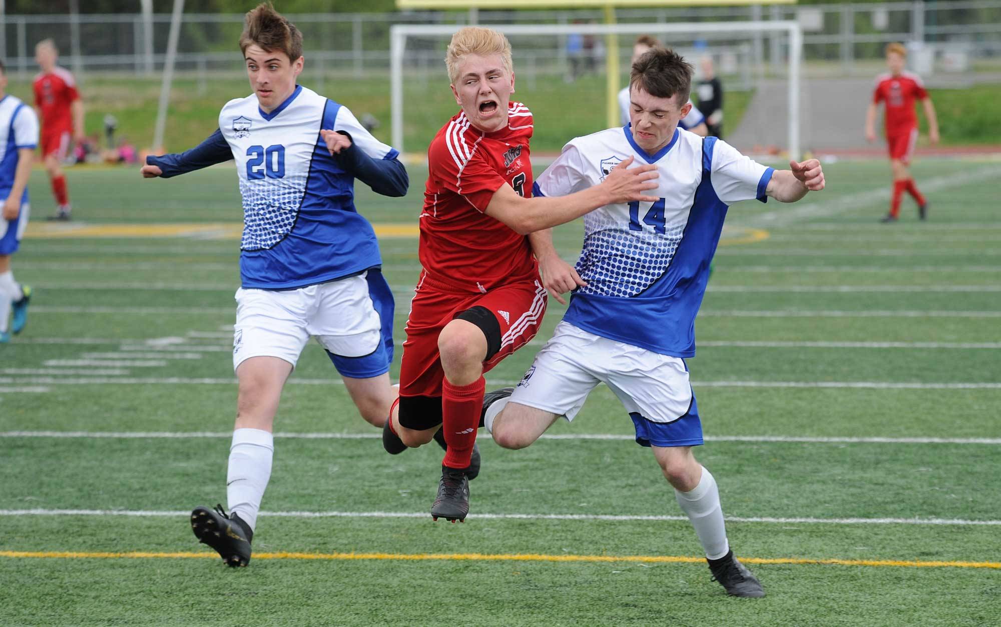 Juneau-Douglas’ Richard Lehner blasts between Palmer’s Logan Crews, left and Ian Roberts during the first half of their ASAA/First National Bank Alaska soccer state championship match Thursday evening at Service High School in Anchorage. (Michael Dinneen | For the Juneau Empire)