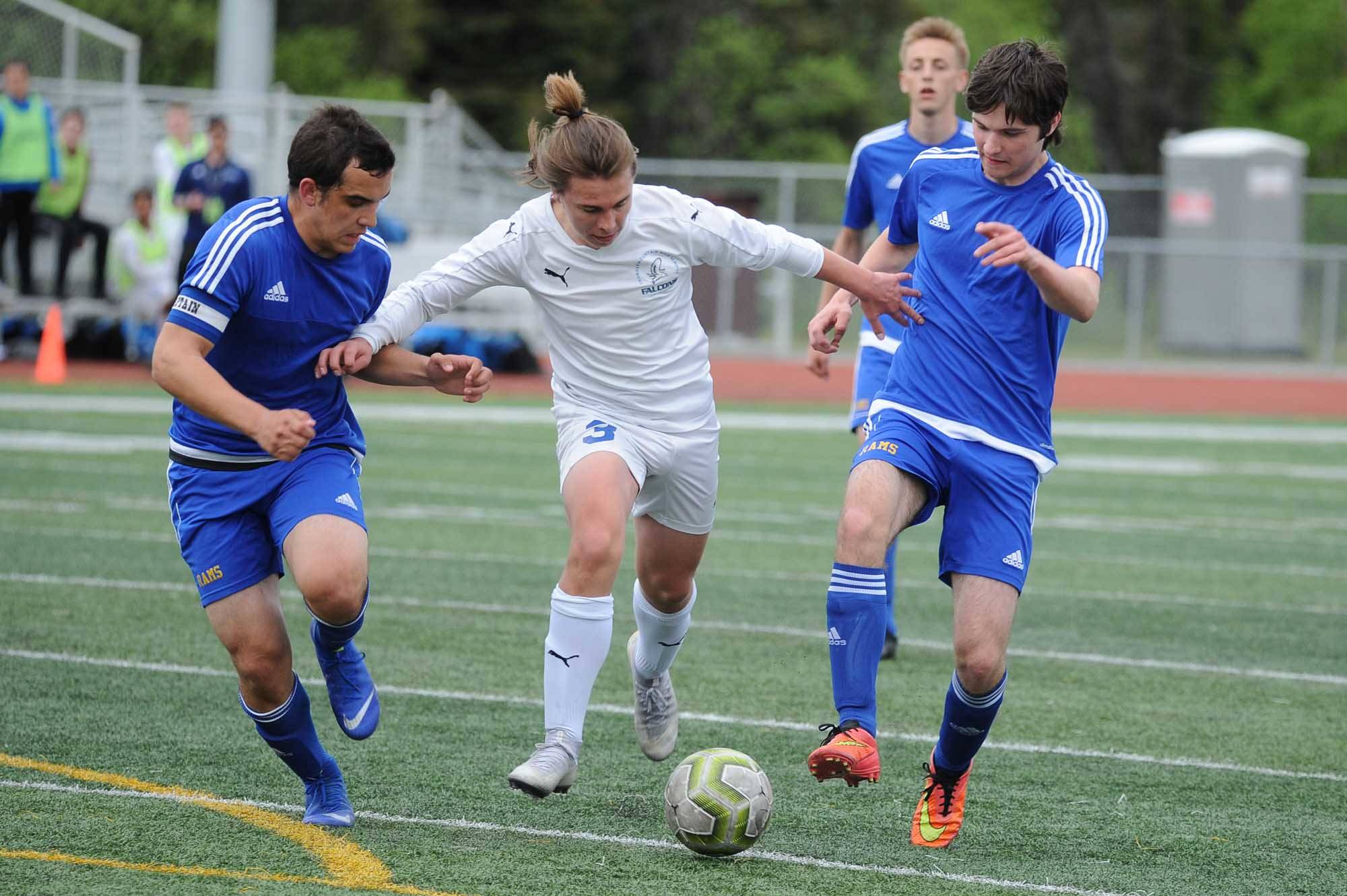 Thunder Mountain’s Gavin Gende keeps a pair of Monroe Catholic players at bay during the first half of their ASAA/First National Bank Alaska soccer state championship match Thursday evening at Service High School in Anchorage. (Michael Dinneen | For the Juneau Empire)