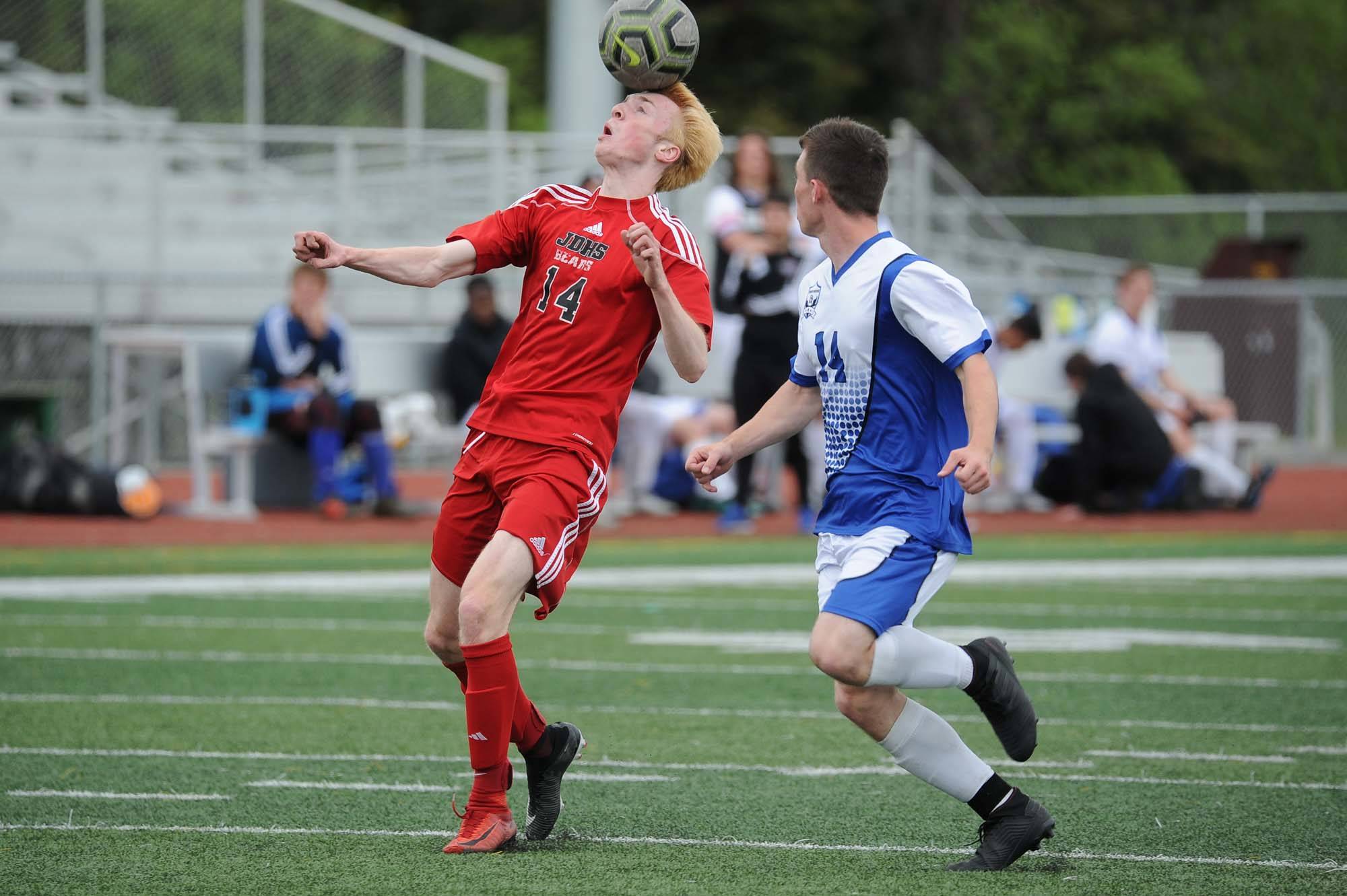 From left, Juneau-Douglas’ Kanon Goetz heads the ball as Palmer’s Ian Roberts looks on during the first half of their ASAA/First National Bank Alaska soccer state championship match Thursday evening at Service High School in Anchorage. (Michael Dinneen | For the Juneau Empire)