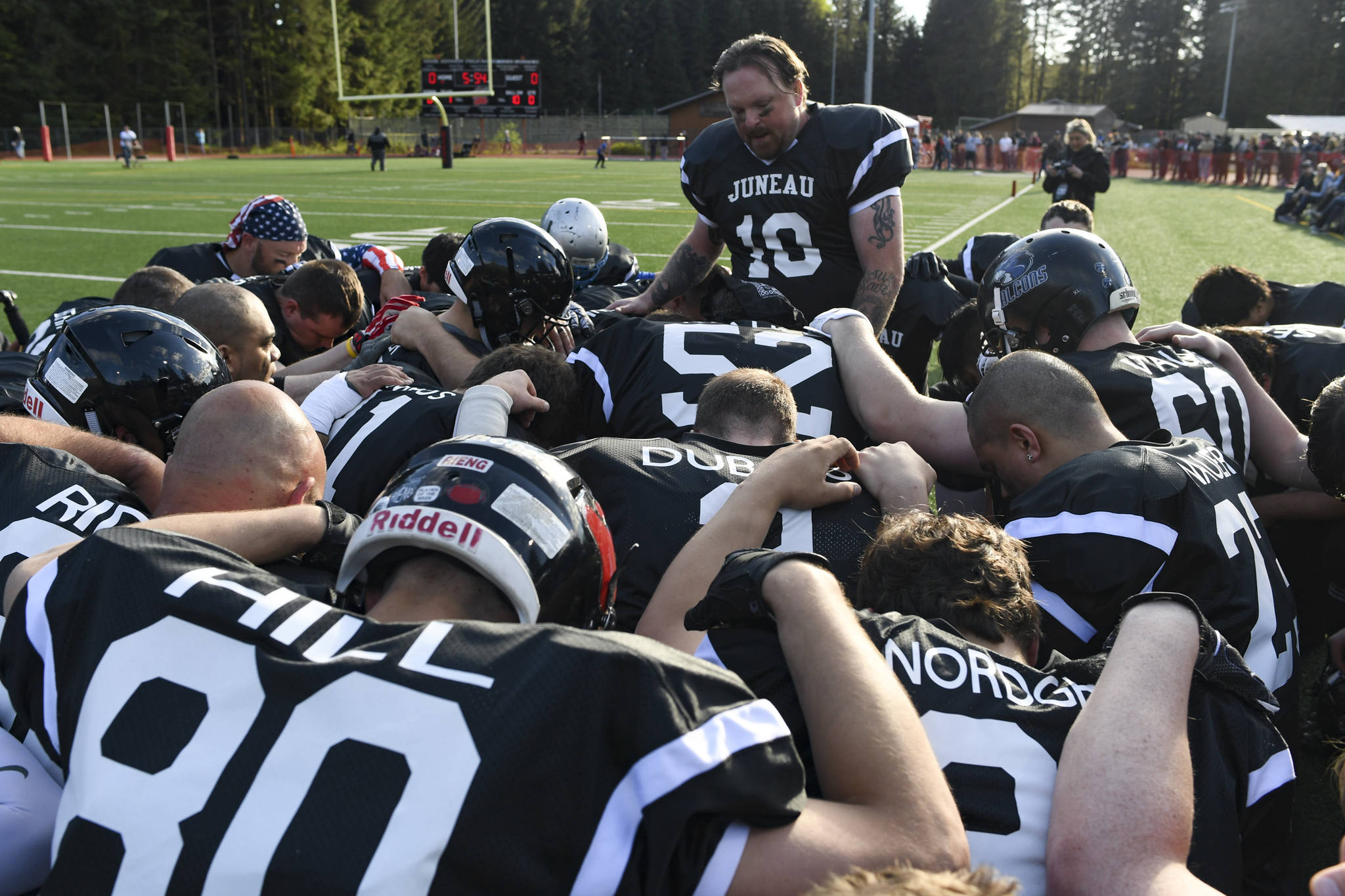 Chris Connally leads a prayer before the Juneau Alumni Football Game with football players, dance team members and cheerleaders from Juneau-Douglas and Thunder Mountain High Schools at Adair-Kennedy Memorial Field on Friday, May 24, 2019. (Michael Penn | Juneau Empire)