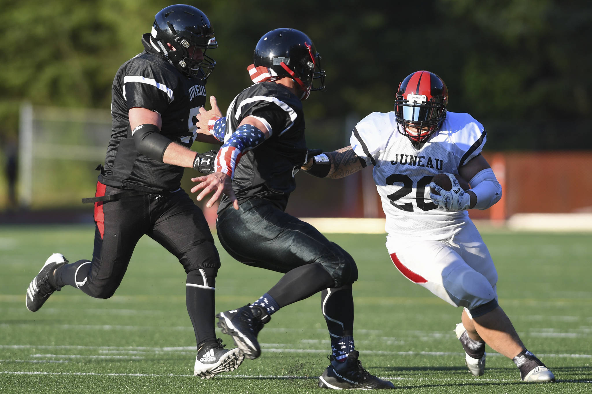 Stars’ Lance Fenumiai, right, is pursued by Legends’ Tommy Penrose, center, and Jake Ritter in the Juneau Alumni Football Game with football players, dance team members and cheerleaders from Juneau-Douglas and Thunder Mountain High Schools at Adair-Kennedy Memorial Field on Friday, May 24, 2019. (Michael Penn | Juneau Empire)
