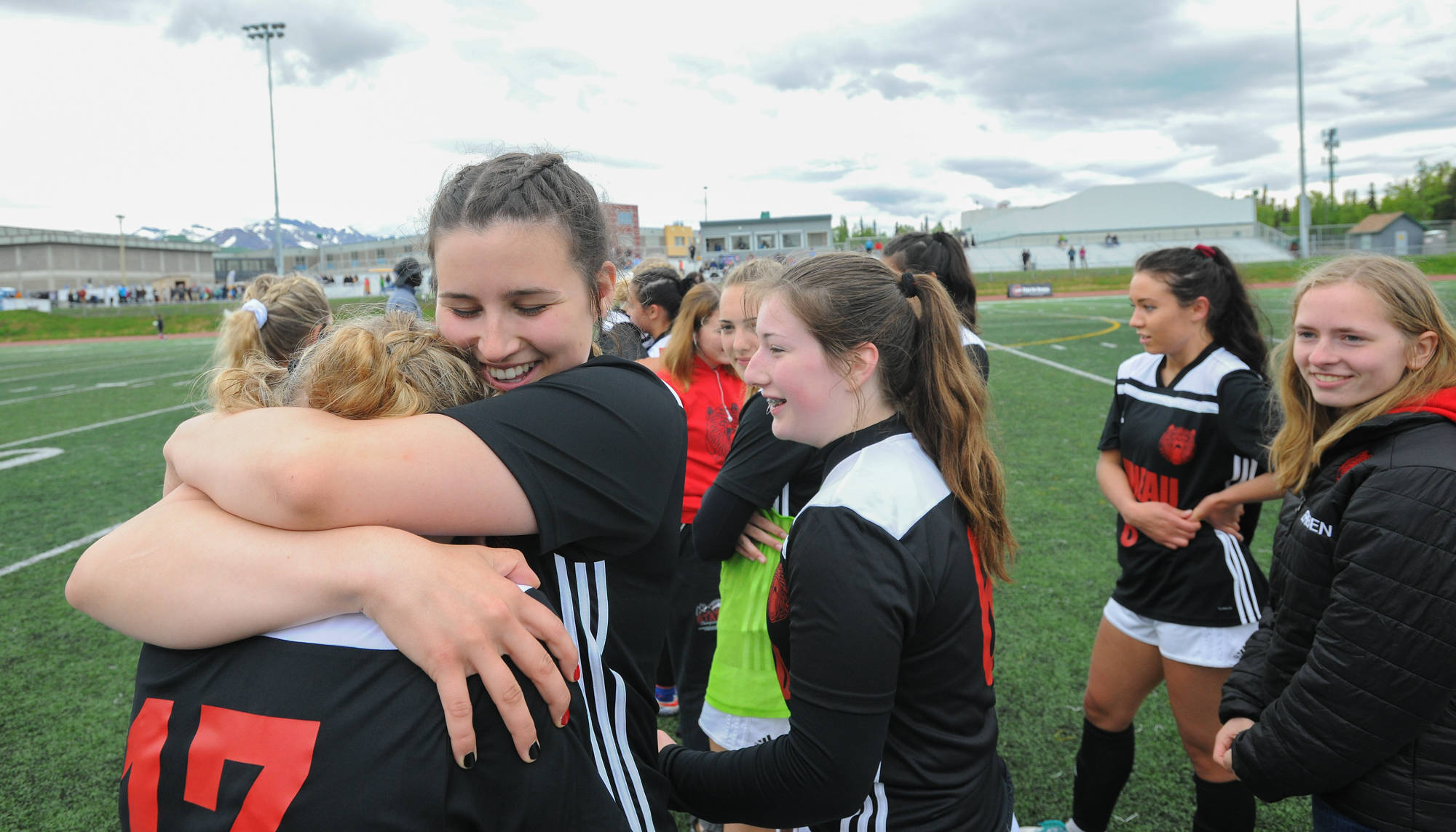 Juneau-Douglas’ Nikki Box, facing camera, hugs teammate Taylor Bentley immediately following the team’s 5-1 win over Soldotna in the ASAA/First National Bank Alaska soccer state championship match Saturday afternoon at Service High School in Anchorage. (Michael Dinneen | For the Juneau Empire)