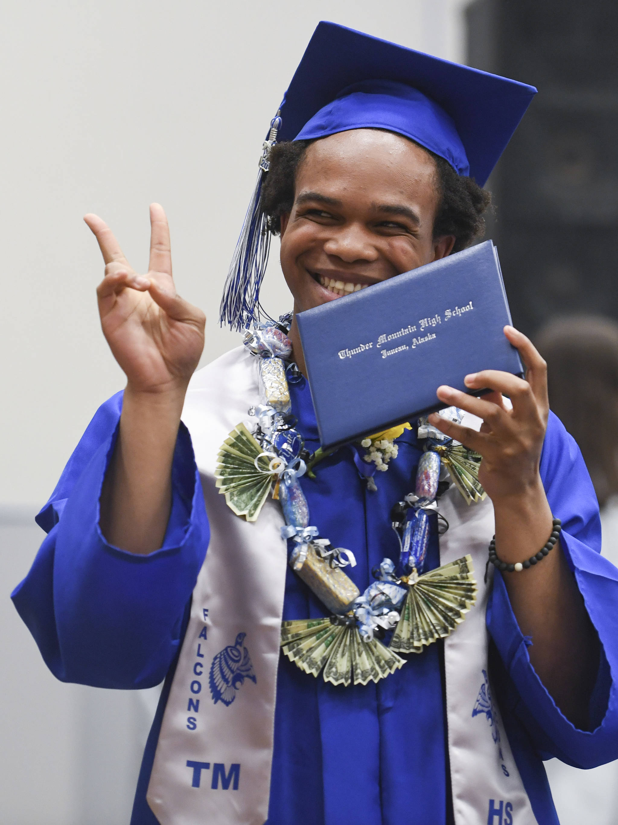 Simon Smith shows off his new diploma while walking off stage during the Thunder Mountain High School graduation on Sunday, May 26, 2019. (Michael Penn | Juneau Empire)