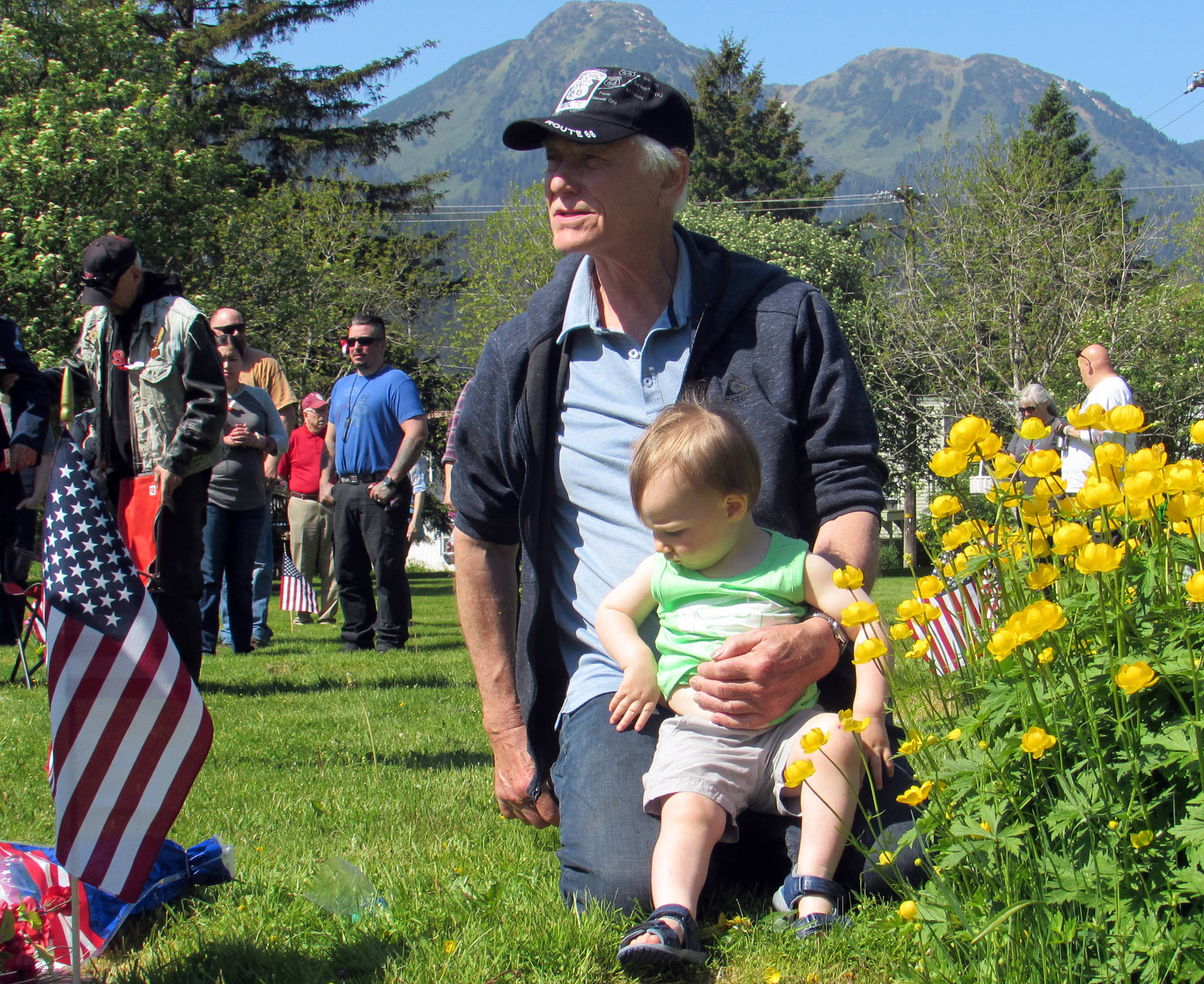 Jim Asper holds his grandson, Jim Reeder, 1, at Evergreen Cemetery during a Memorial Day ceremony the morning of Monday, May 27. (Ben Hohenstatt | Juneau Empire)