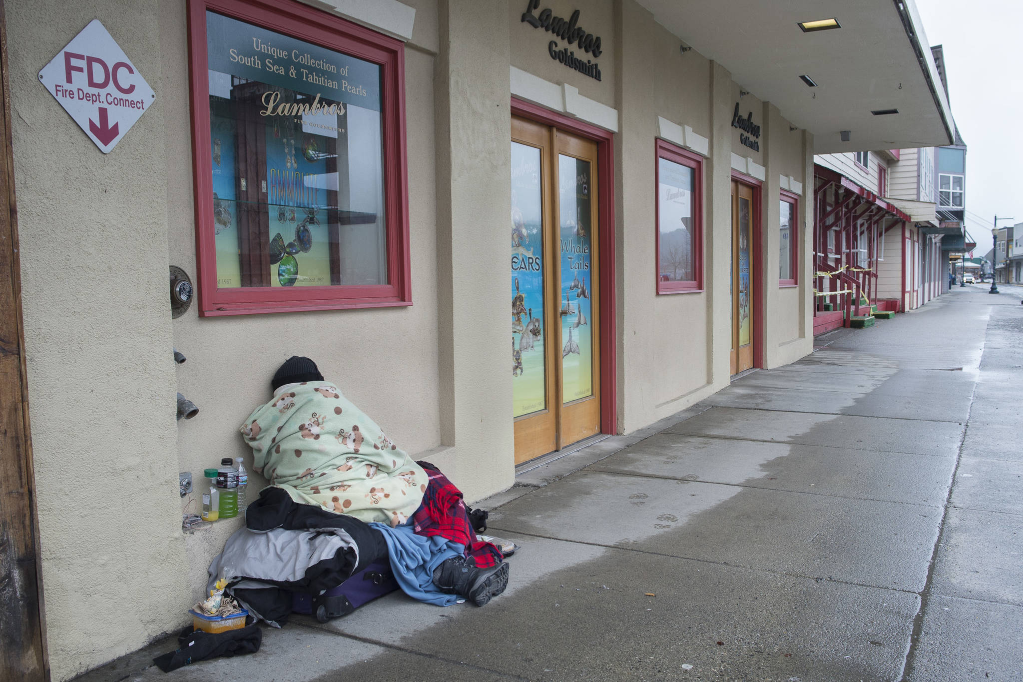 A homeless person sleeps on the sidewalk along South Franklin Street on Friday, March 15, 2019. (Michael Penn | Juneau Empire File)
