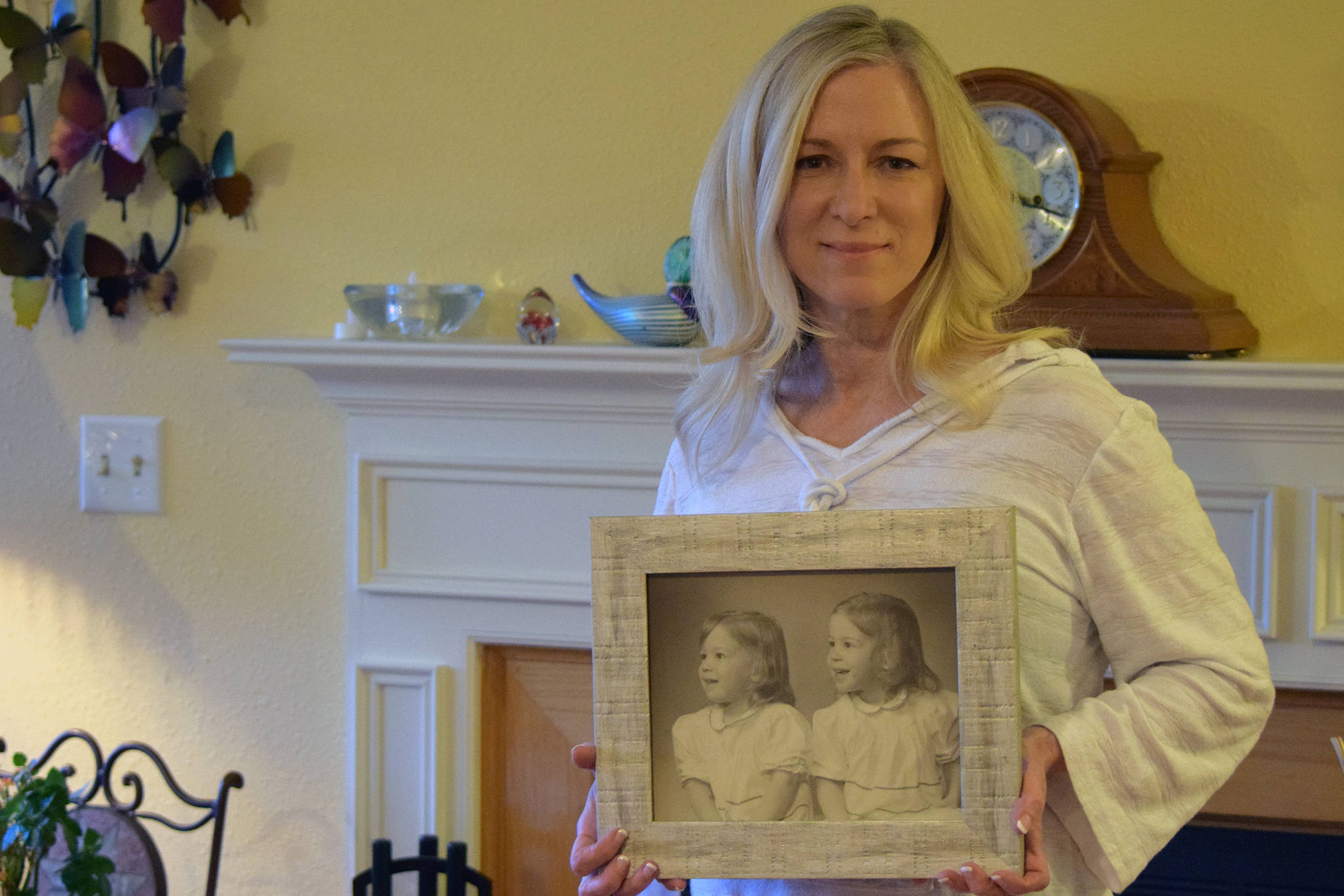Brenda Bowers holds up a photo of herself and her then-sister Bonnie at Brenda’s Juneau home on May 31, 2019. (Ben Hohenstatt | Juneau Empire)