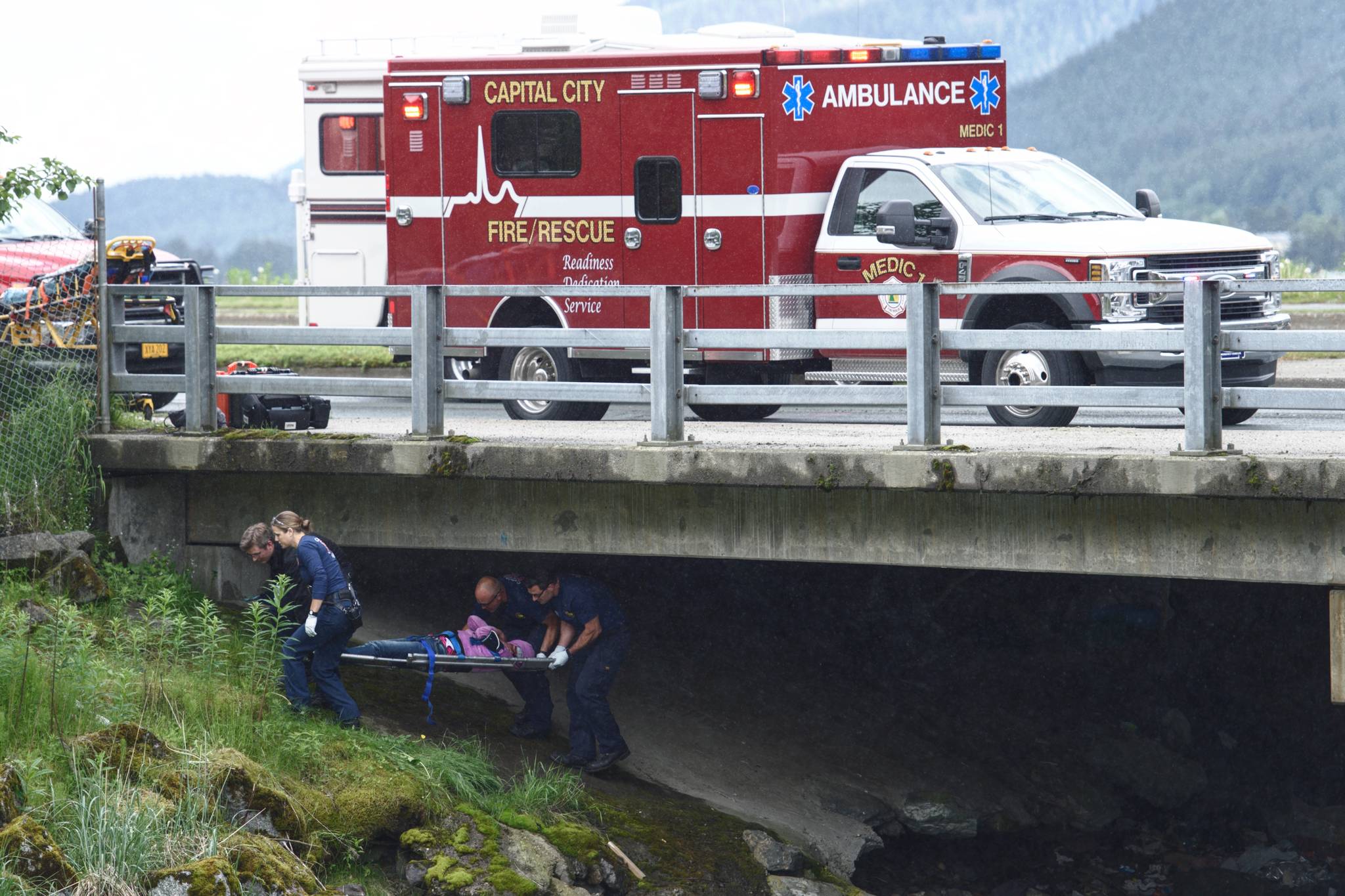 Capital City Fire/Rescue personnel carry out a person from under the Gold Creek Bridge at Egan Drive on Tuesday, June 4, 2019. (Michael Penn | Juneau Empire)
