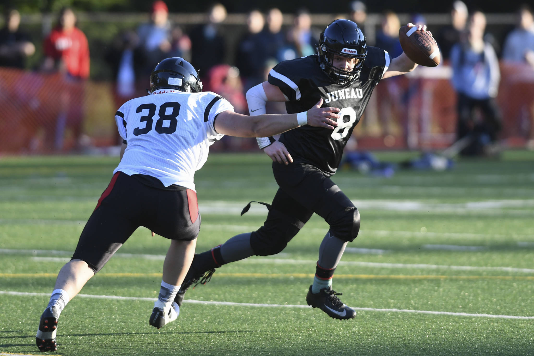Legends’ Stefan Jones, right, is pursued by Stars’ Dylan Skrzynski in the Juneau Alumni Football Game on Friday, May 24, 2019. Jones is wearing one of 40 new helmets a group of alumni helped purchase that will be donated to the high school program. (Michael Penn | Juneau Empire File)