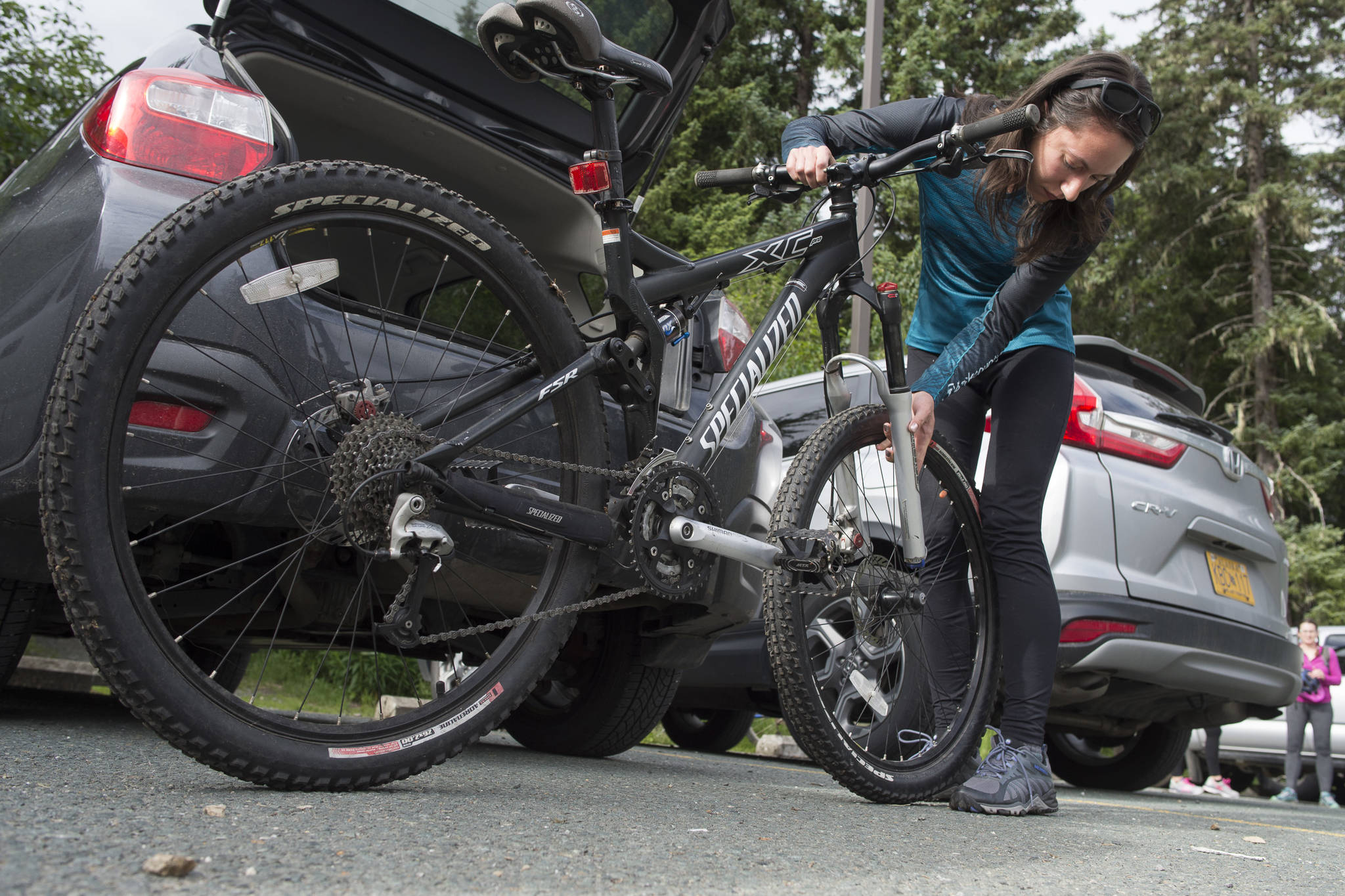 Deborah Reid attaches the front wheel to her mountain bicycle after arriving for a women’s mountain bike ride at Dredge Lakes on Thursday, June 13, 2019. (Michael Penn | Juneau Empire)