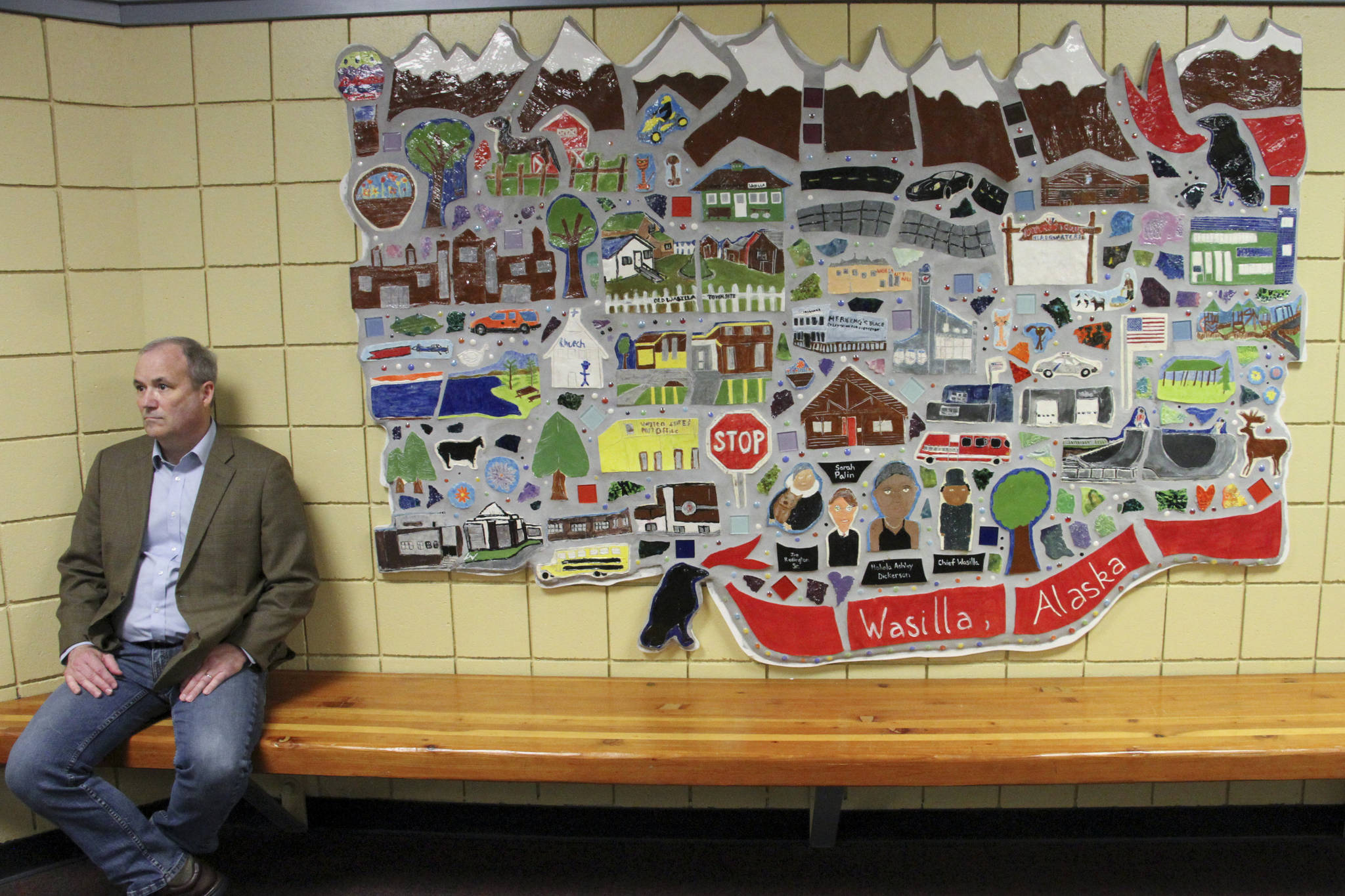 This June 14, 2019, photo shows Jeff Turner, the deputy communications director for Alaska Gov. Mike Dunleavy, sitting next to artwork displayed at Wasilla Middle School in Wasilla, Alaska. Dunleavy has called lawmakers into special session in Wasilla beginning July 8, but some lawmakers have expressed concerns over security and logistics with the location more than 500 miles from the state capital of Juneau, Alaska. (AP Photo/Mark Thiessen)