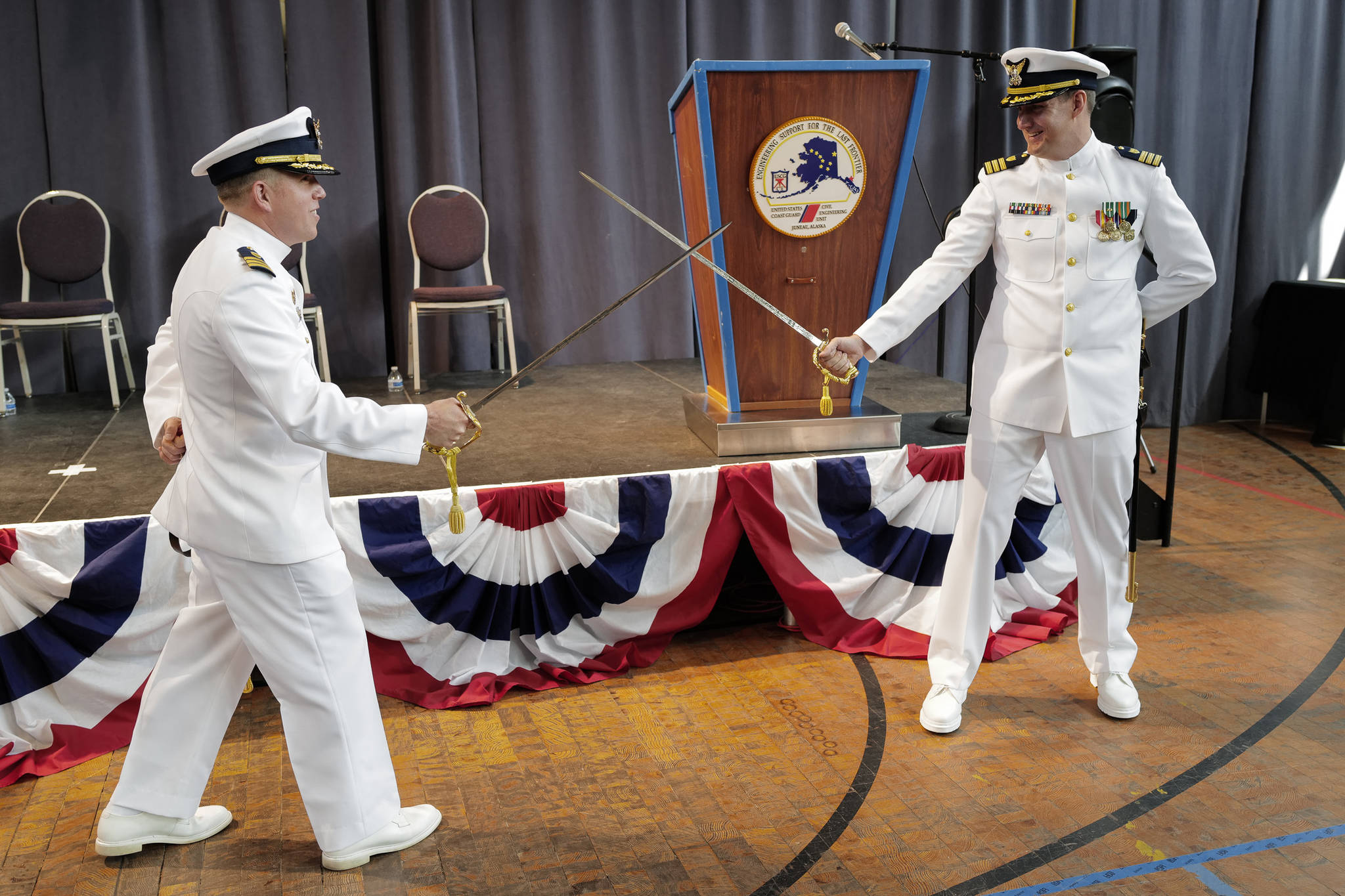 U.S. Coast Guard Commander Andrew S. Joca, left, playfully duels with Commander Nathan L. Rumsey, right, after a Change of Command ceremony at the Juneau Arts and Culture Center on Thursday, June 20, 2019. Outgoing Commander Joca assumed command of the Civil Engineering Unit in Juneau in May 2016 and will become the Director of Operational Logistics in Norfolk, Virginia. Commander Rumsey’s most recent assignment was the Engineer Officer and Facilities Engineer at Sector New York. Joca carries his father’s sword who was a Navy veteran of the Vietnam War. (Michael Penn | Juneau Empire)