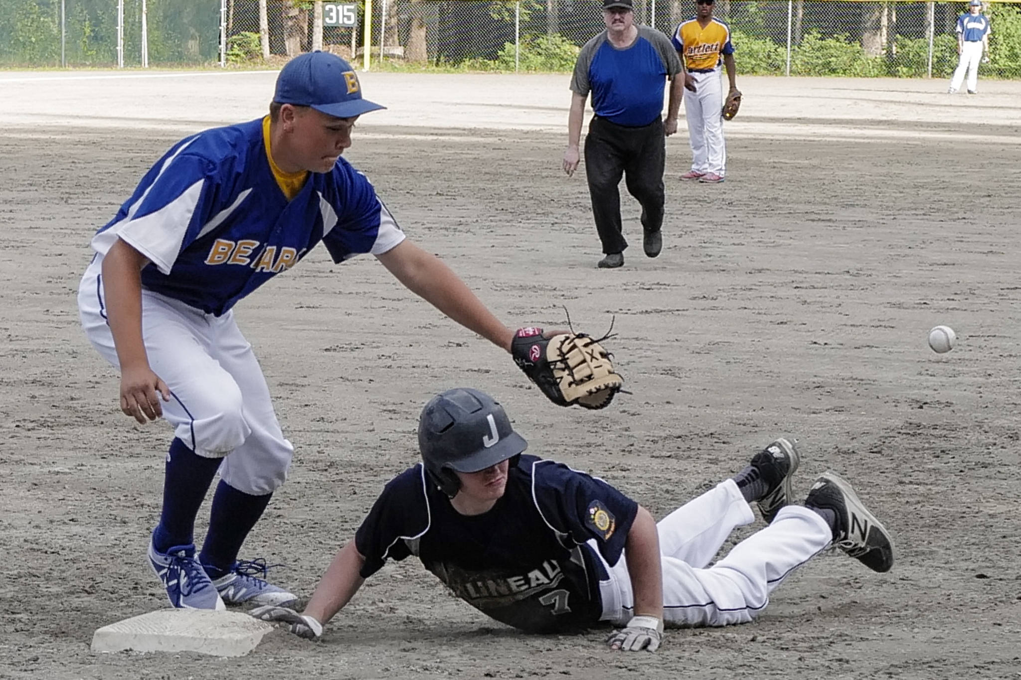 Juneau’s Brock McCormick dives safely back to first base as the ball gets by Bartlett’s Taylor McCartin the fourth inning in Legion League baseball at Adair-Kennedy Memorial Park on Friday, June 21, 2019. (Michael Penn | Juneau Empire)