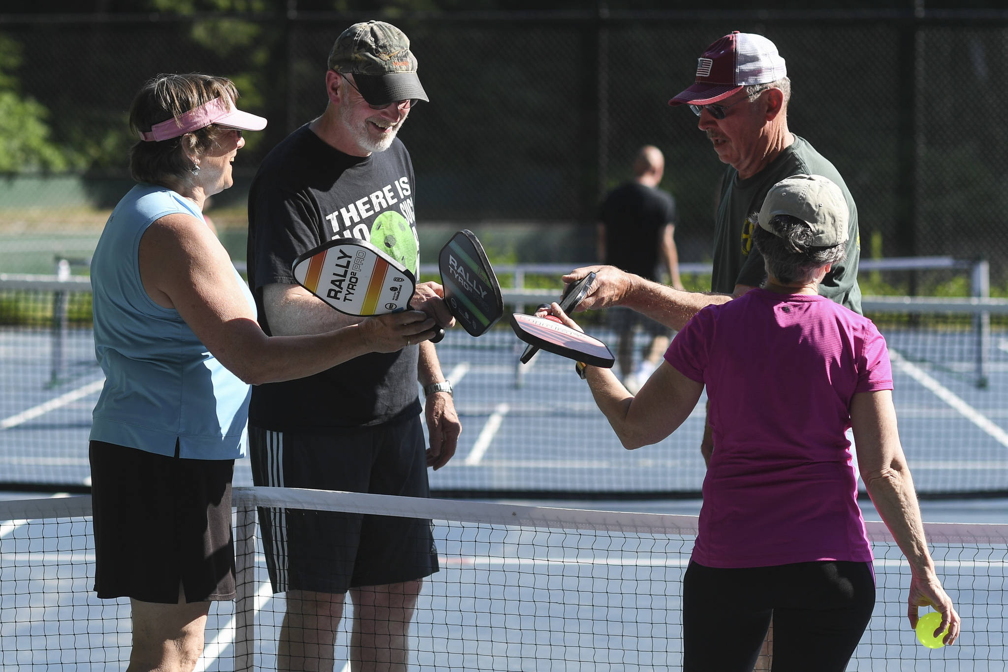 Pickleball players touch paddles after a match instead of giving handshakes at the Cope Park tennis courts on Wednesday, June 26, 2019. (Michael Penn | Juneau Empire)