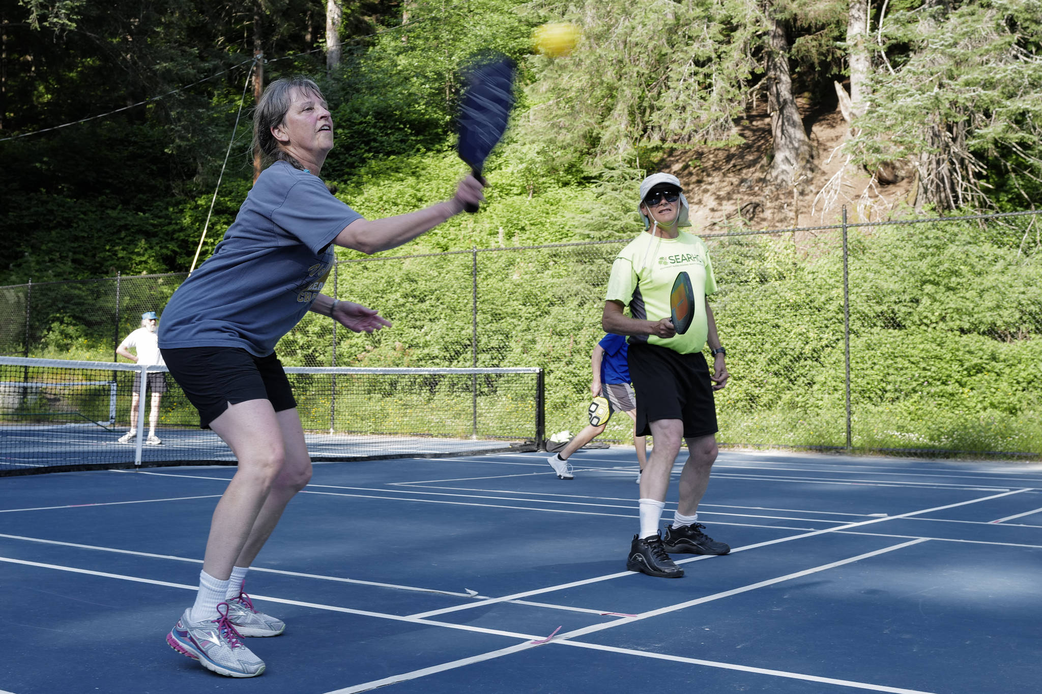 Christi Herrea plays the ball as teammate David Job watches during a pickleball match at the Cope Park tennis courts on Wednesday, June 26, 2019. (Michael Penn | Juneau Empire)