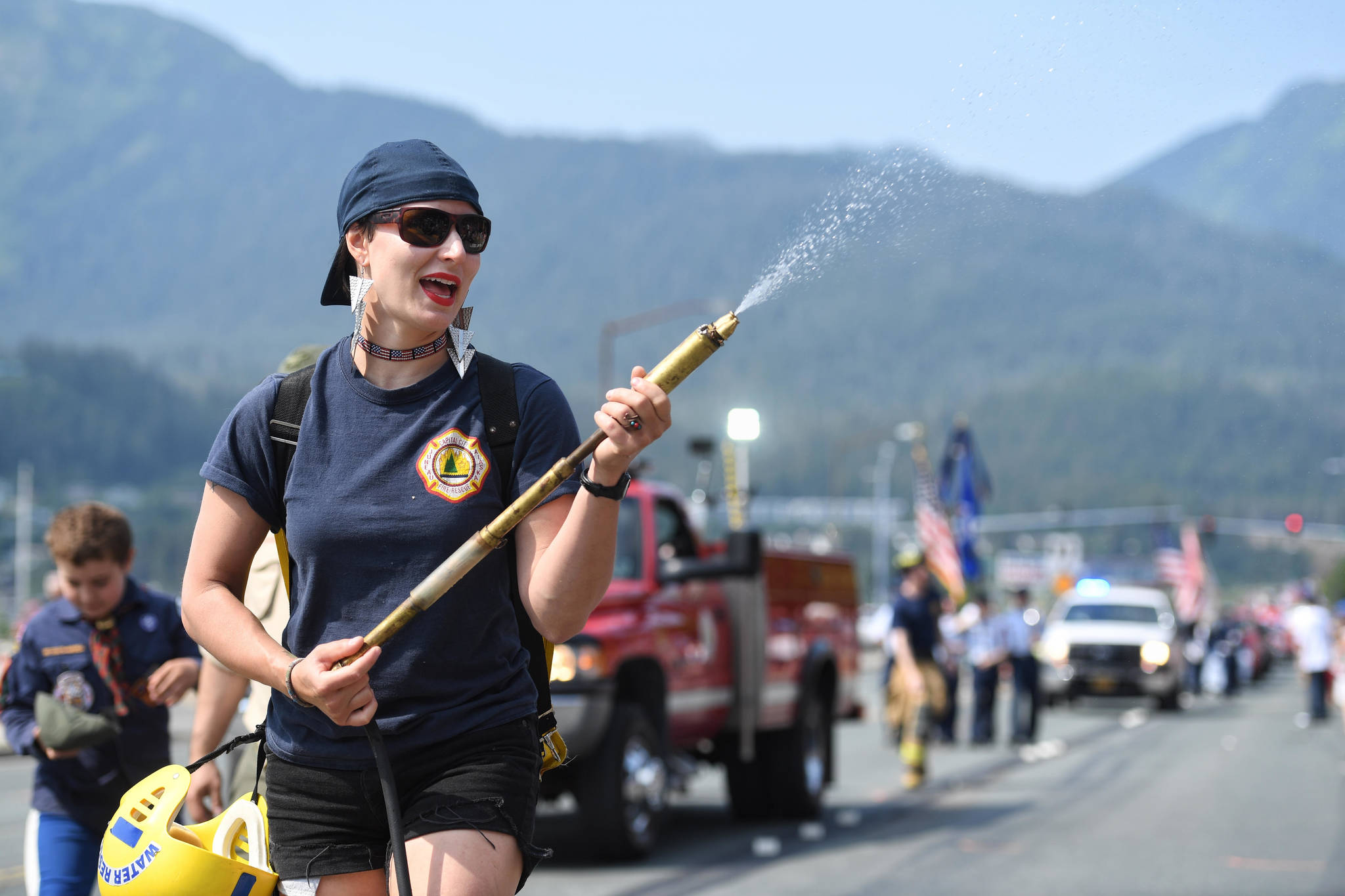 Meghan DeSloover of Capital City Fire/Rescue keeps people cool during the Fourth of July parade on Thursday, July 4, 2019. (Michael Penn | Juneau Empire)