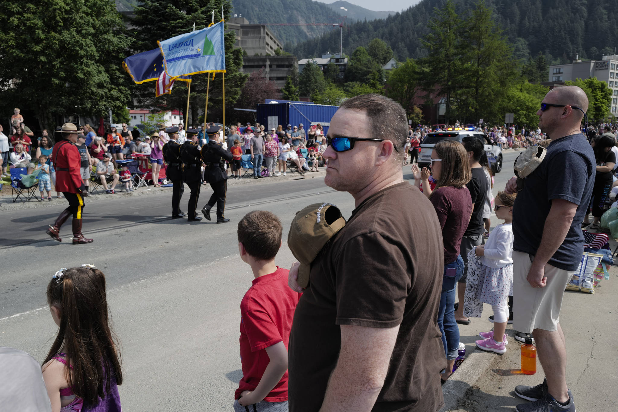 Veteran Chuck McCracken and Ruben Boudreaux, right, currently in the Coast Guard, take their hats off as a Juneau Police Department Honor Guard and Canadian Mounties pass by during the Juneau Fourth of July Parade on Thursday, July 4, 2019. (Michael Penn | Juneau Empire)