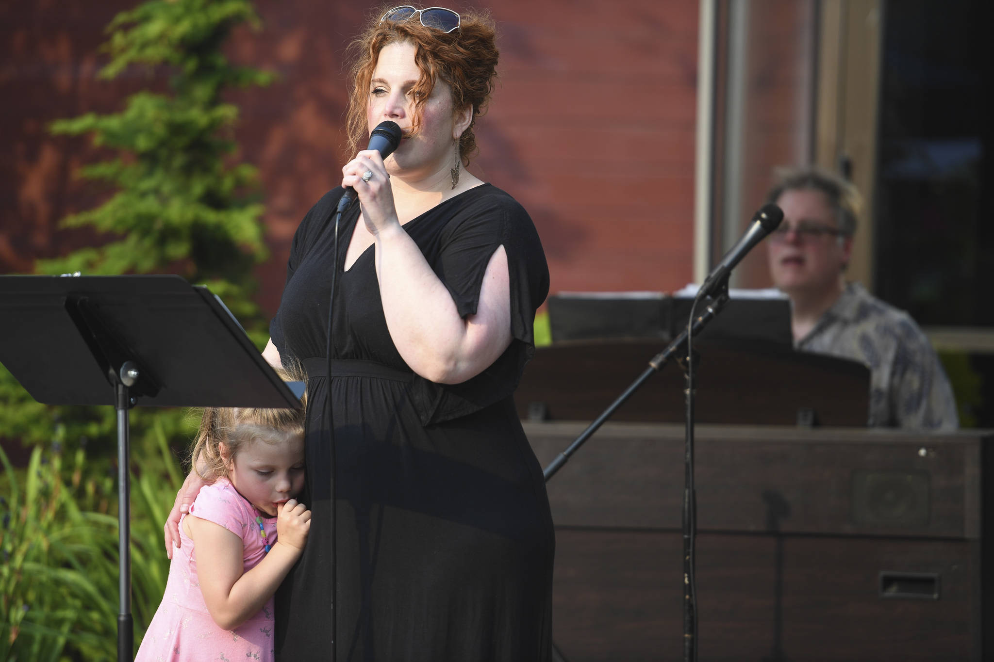 Margeaux Ljungberg sings as her daughter, Adelaide, 4, hangs close during a Summer Block Party at Centennial Hall on Friday, July 5, 2019. Tom Locher, music director for Juneau Cabaret, provides backing on piano. (Michael Penn | Juneau Empire)