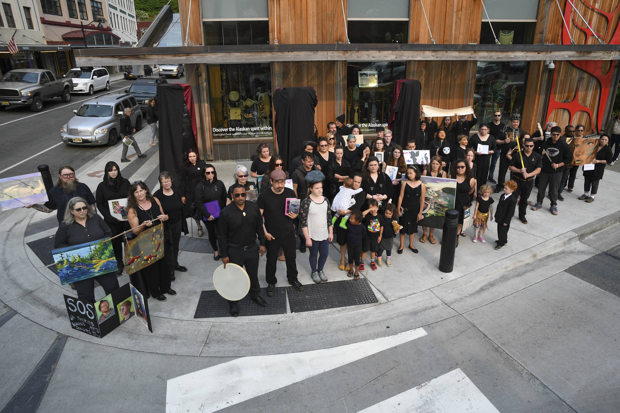 About 50 artists stand with their work in front of the Sealaska Heritage Institute on Tuesday, July 9, 2019, to protest heavy cuts to state arts programs. (Michael Penn | Juneau Empire)
